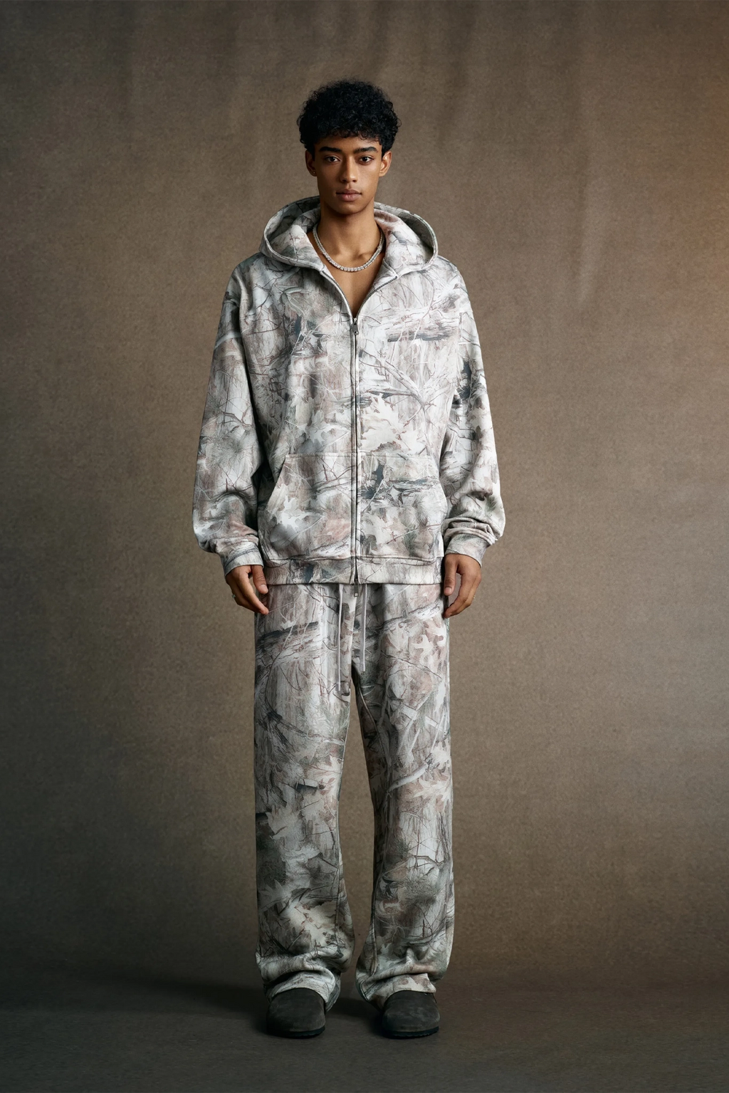 Person wearing a matching camouflage hoodie and pants set against a plain background
