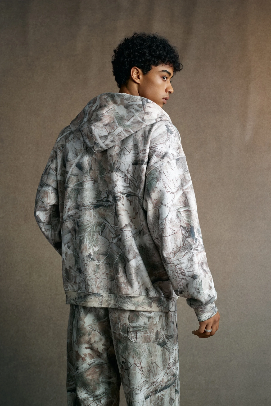 Person wearing a camouflage outfit against a plain background