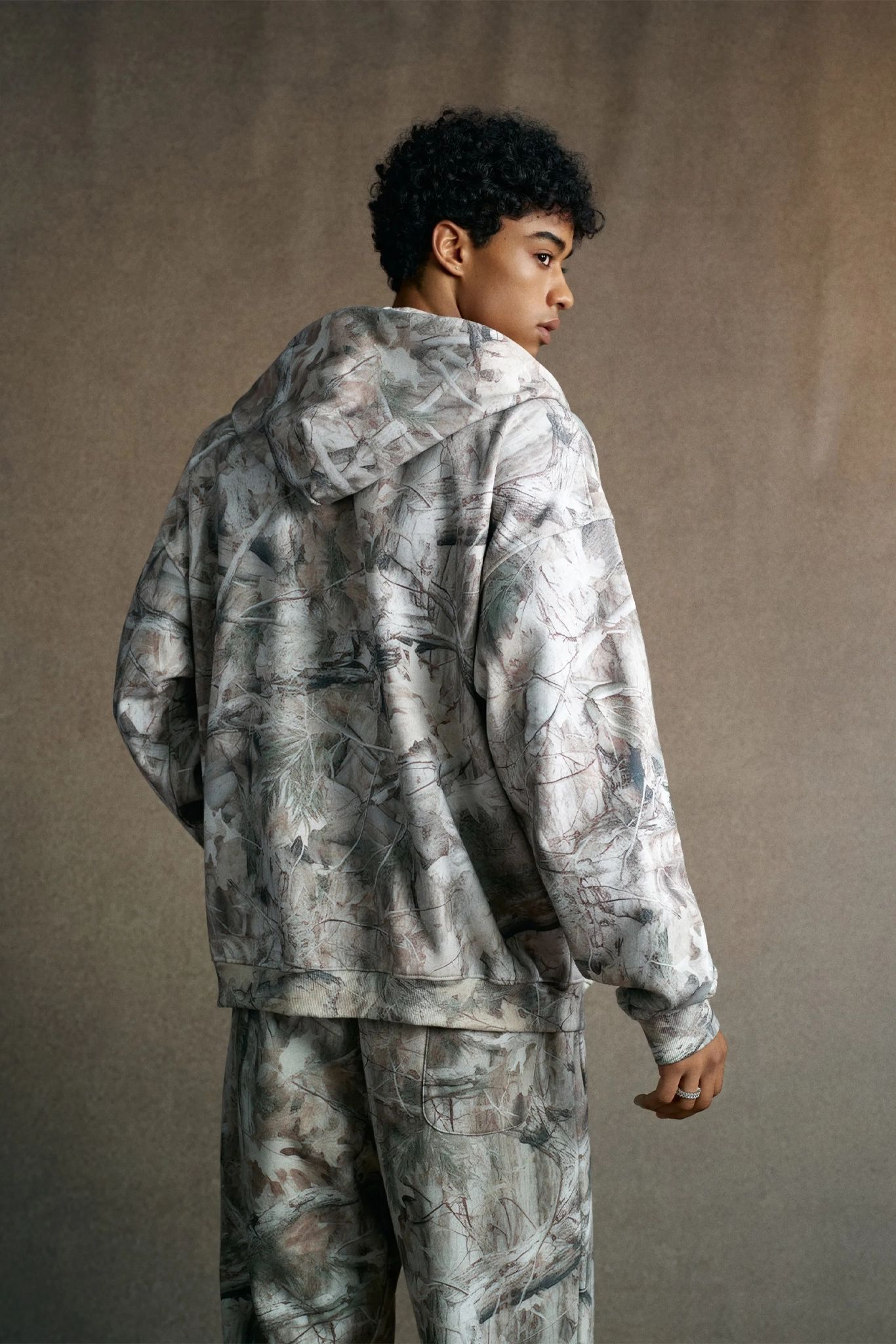 Person wearing a camouflage outfit against a plain background