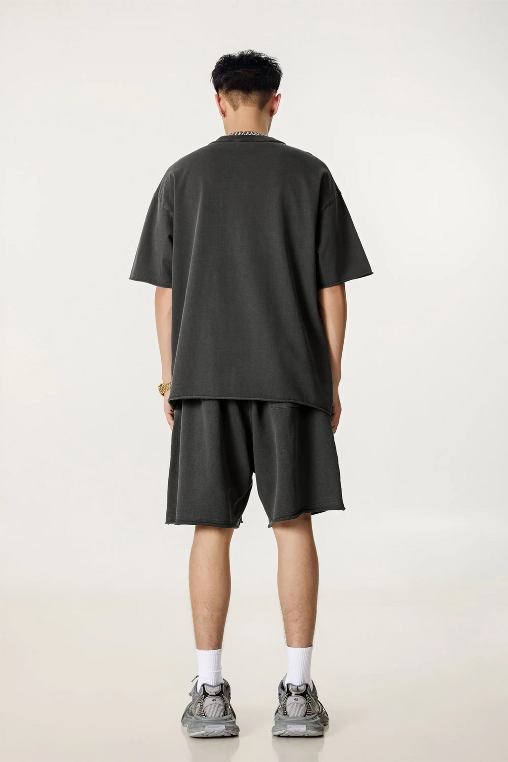 Person wearing a dark gray t-shirt and shorts set on a white background