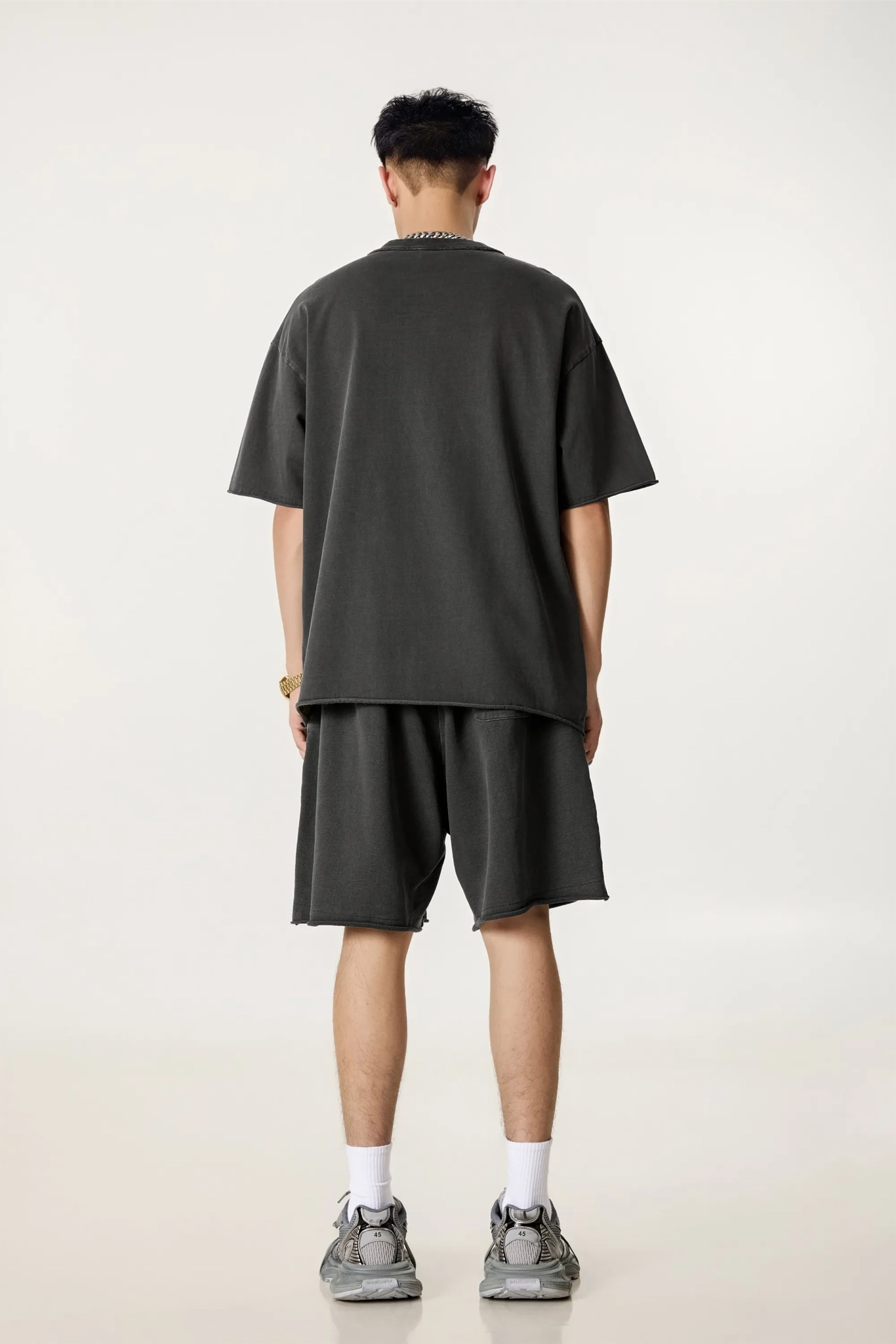 Person wearing a dark gray t-shirt and shorts set on a white background