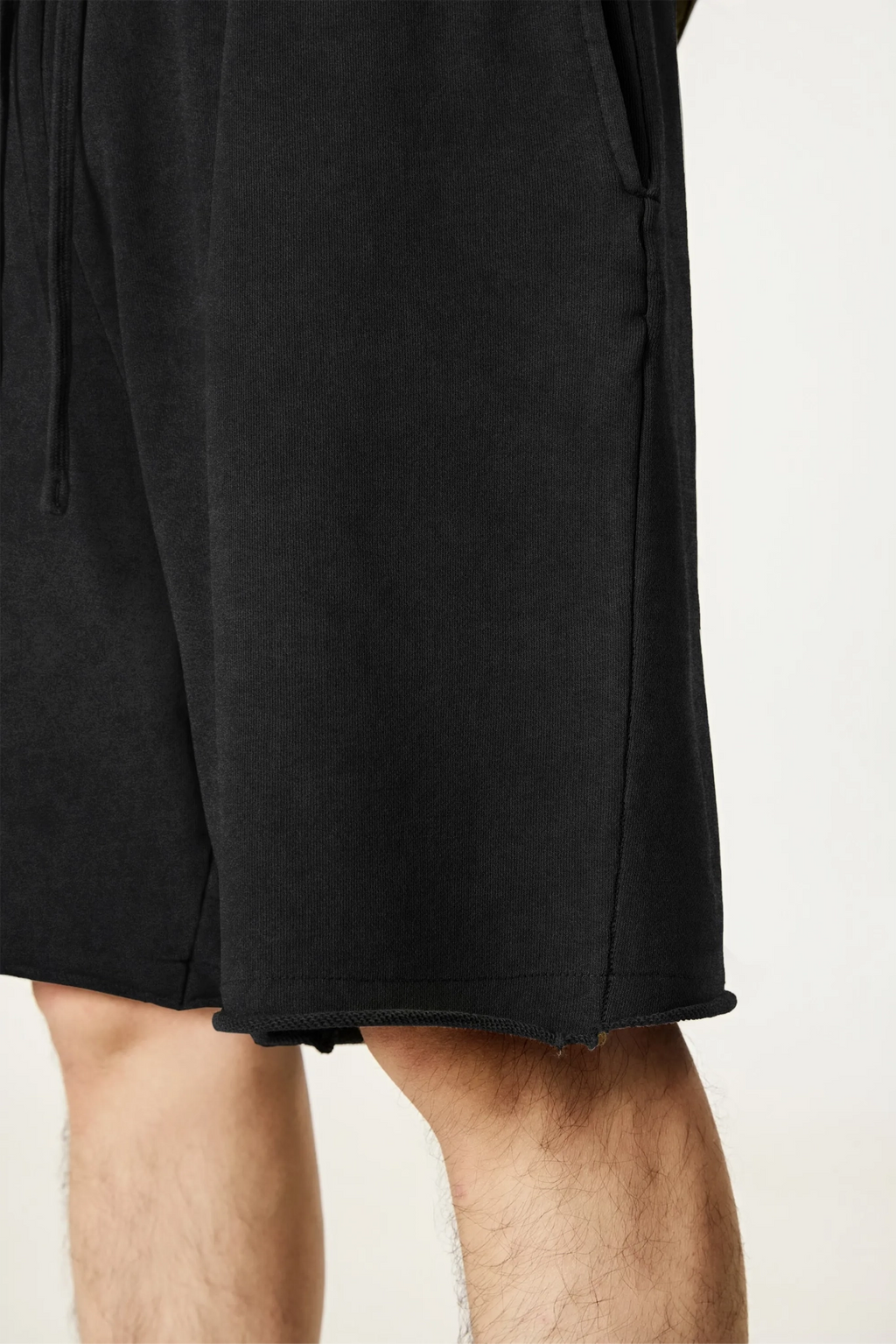 Black shorts worn by a person on a light beige background