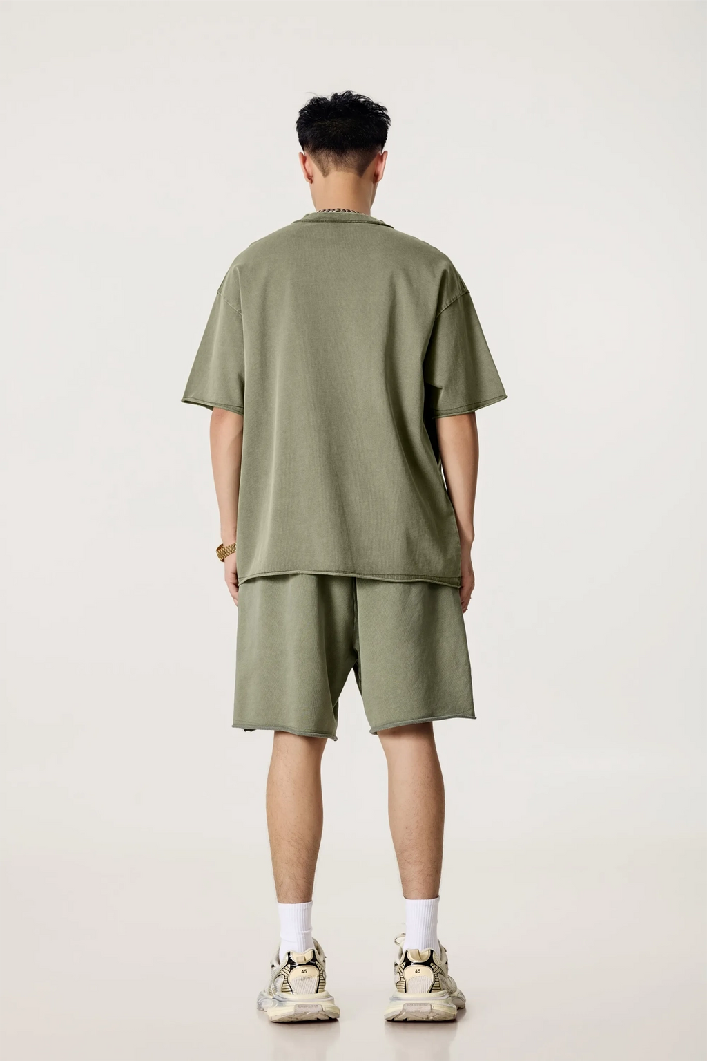 Person wearing an olive green t-shirt and shorts set on a white background