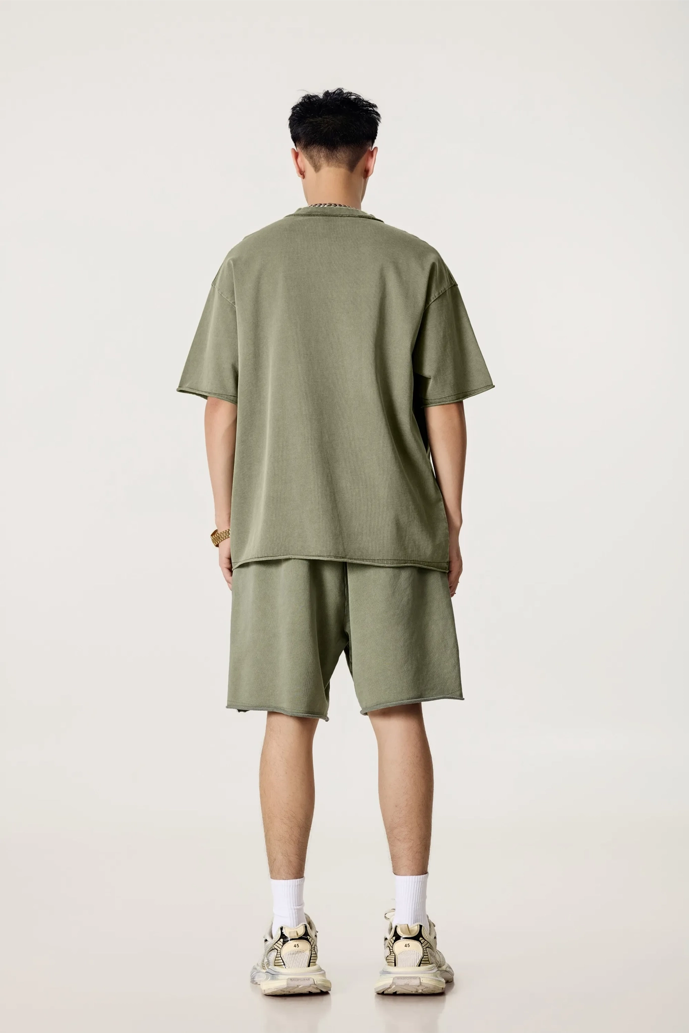 Person wearing an olive green t-shirt and shorts set on a white background