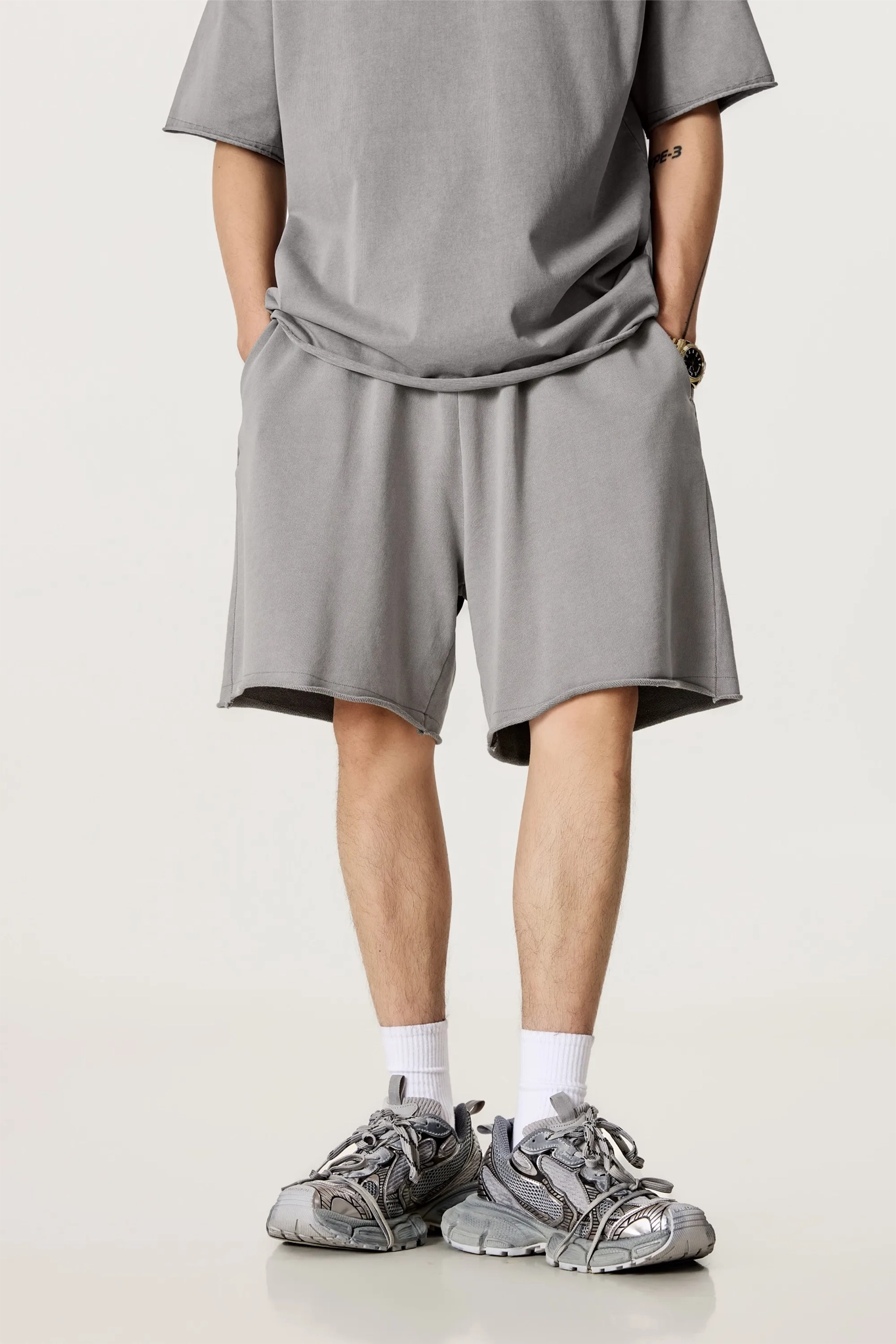 Person wearing a gray outfit with shorts and sneakers on a white background