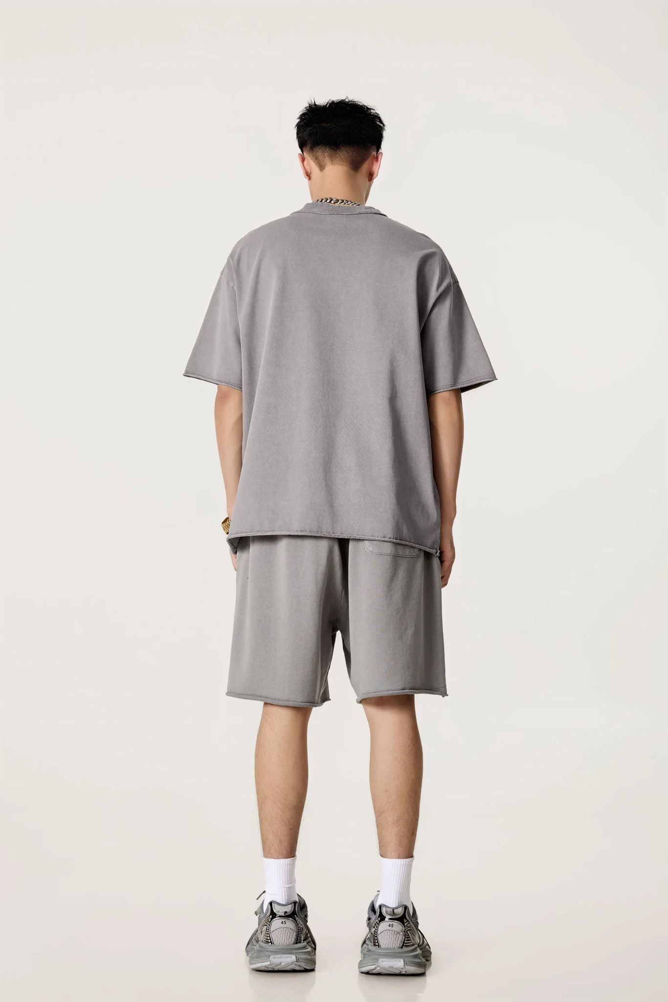 Person wearing a gray outfit standing against a white background