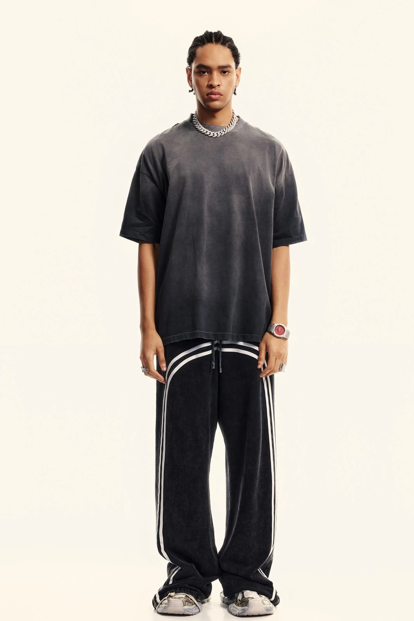 Person wearing a dark gray t-shirt and black pants with white stripes on a white background