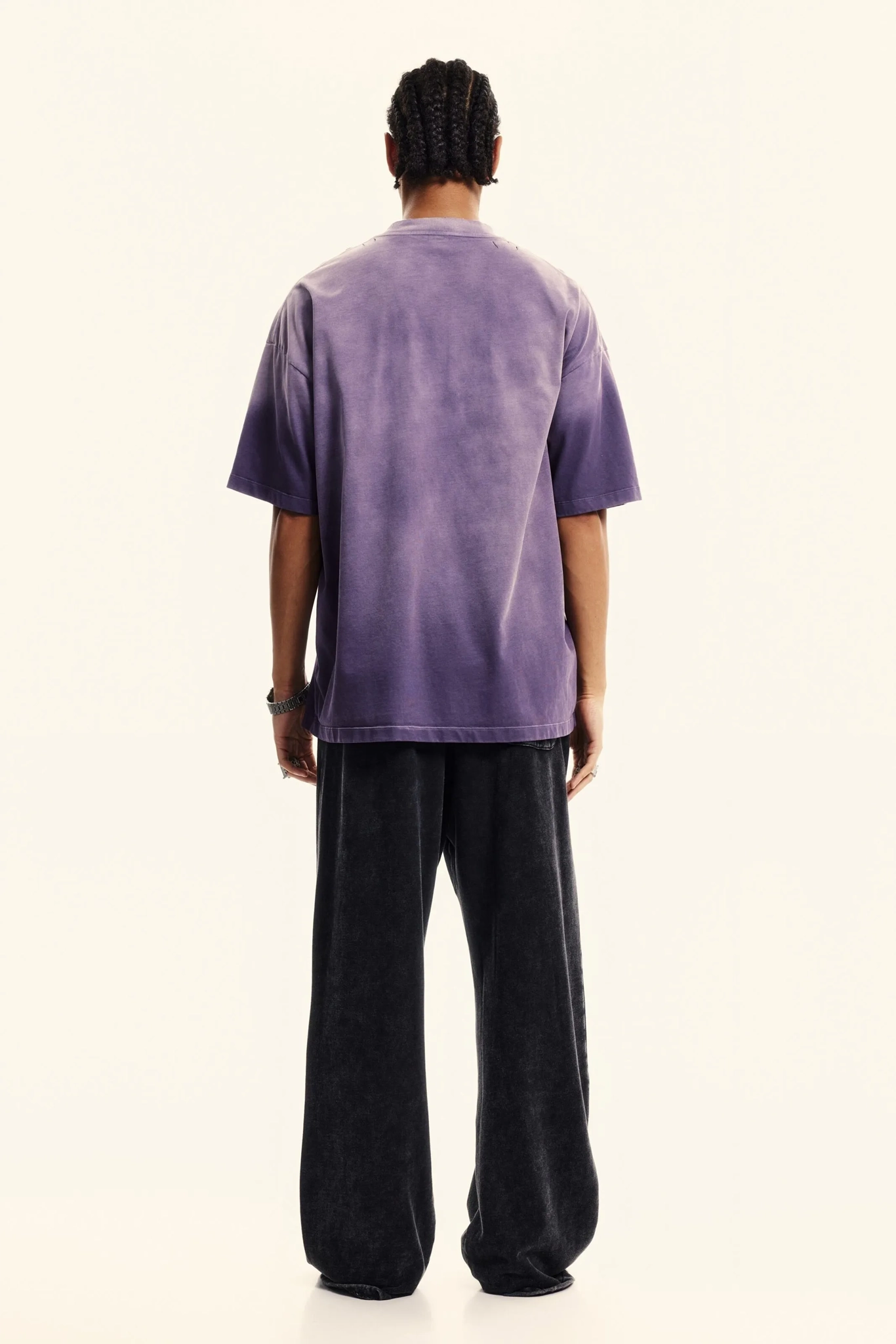 Person wearing a purple t-shirt and black pants on a white background
