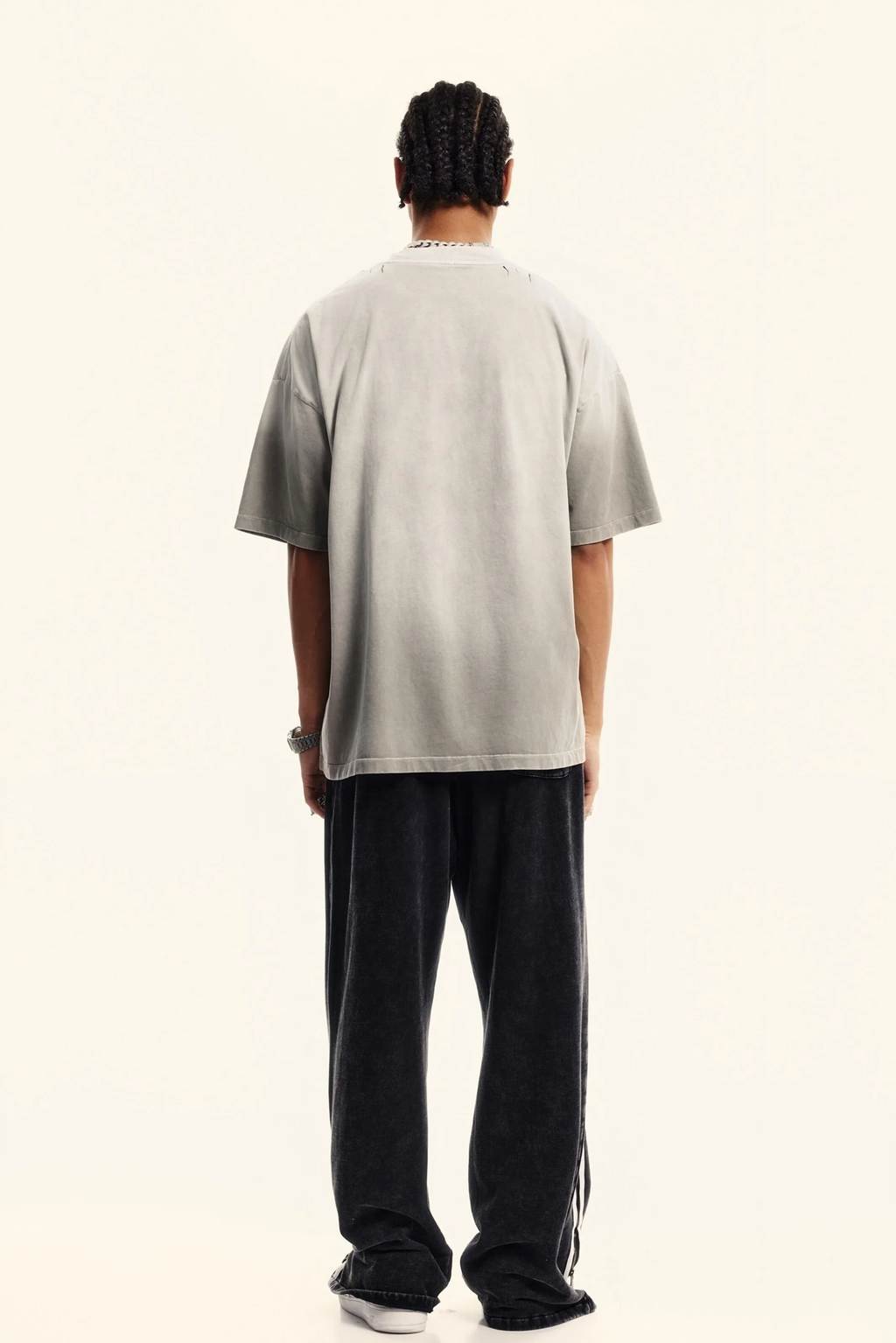 Person wearing a light gray t-shirt and black pants on a white background