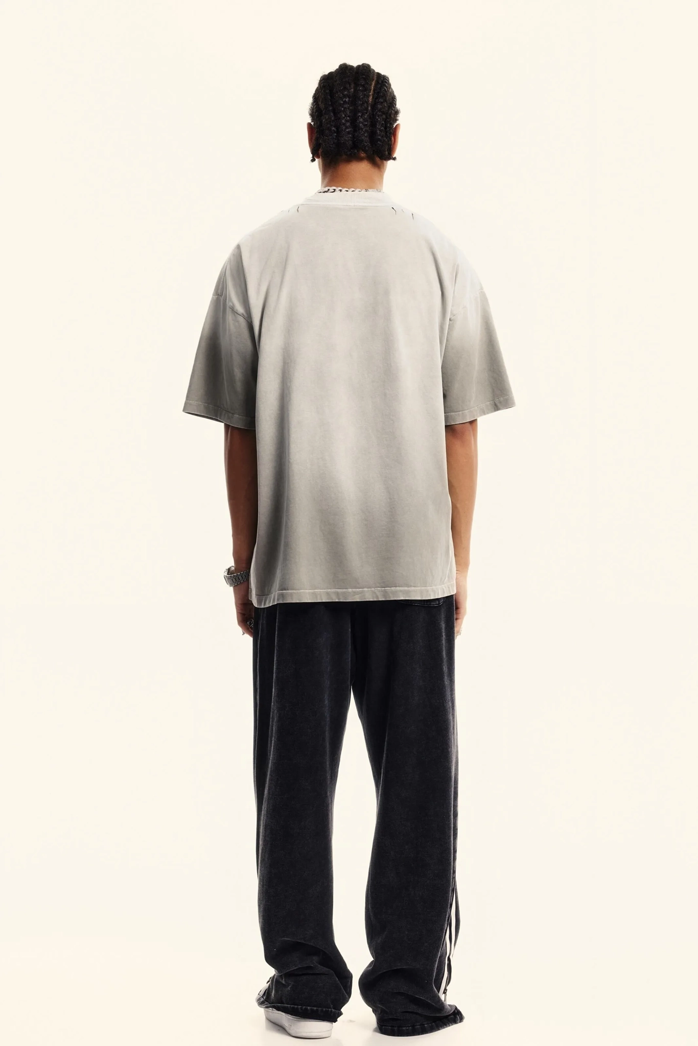 Person wearing a light gray t-shirt and black pants on a white background