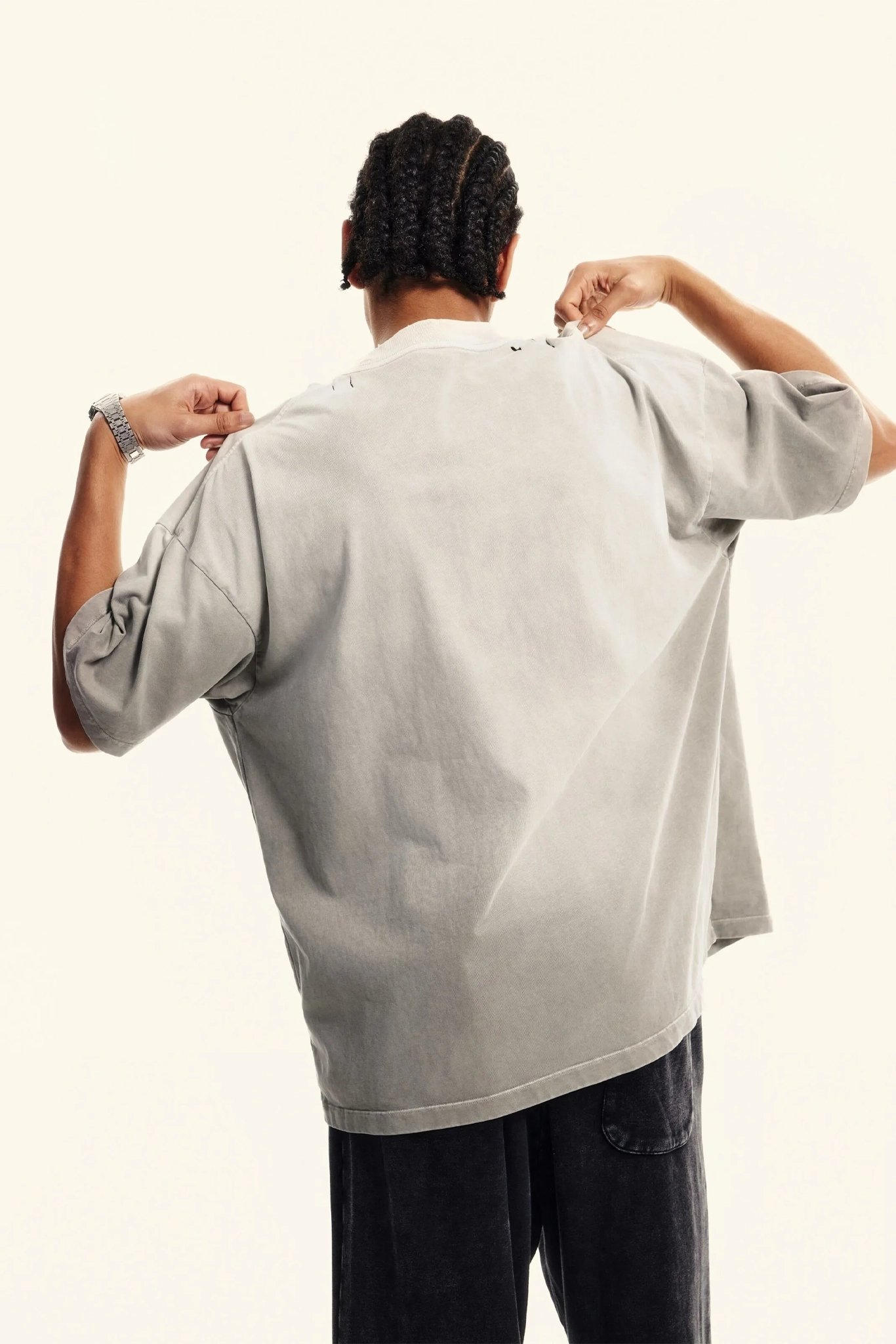 Person wearing a light gray oversized shirt on a plain background