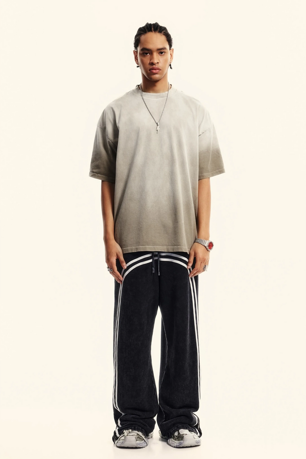 Person wearing a beige shirt and black pants with white stripes on a white background