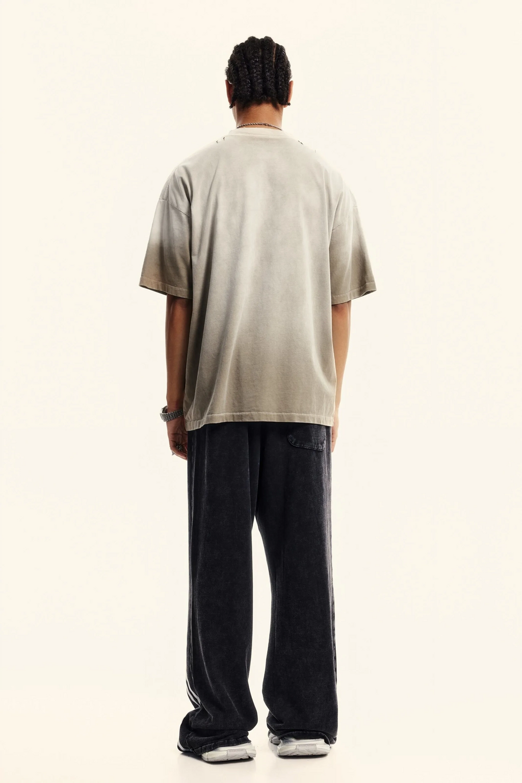 Person wearing a beige t-shirt and dark pants on a white background