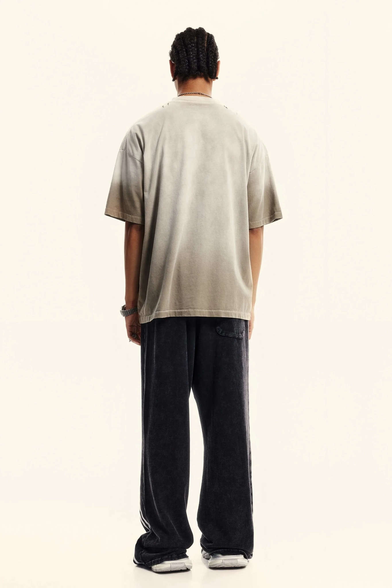 Person wearing a beige t-shirt and dark pants on a white background