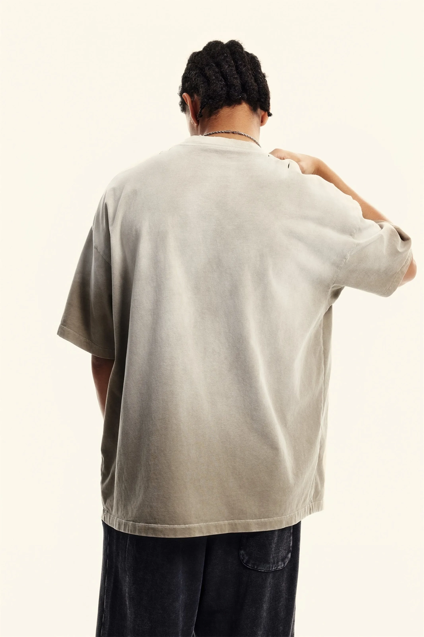Person wearing a beige oversized shirt on a plain background