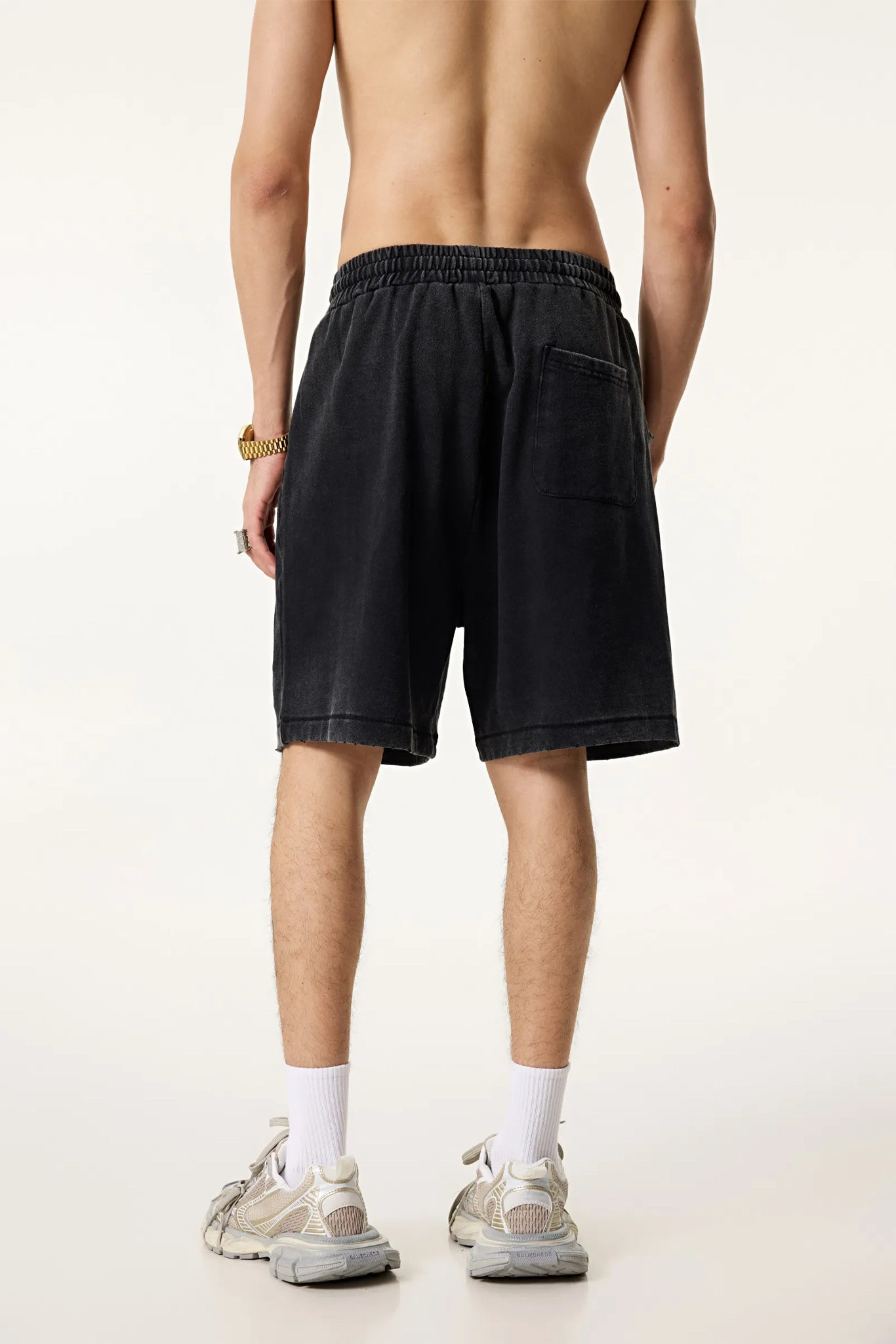 Person wearing black shorts on a plain background