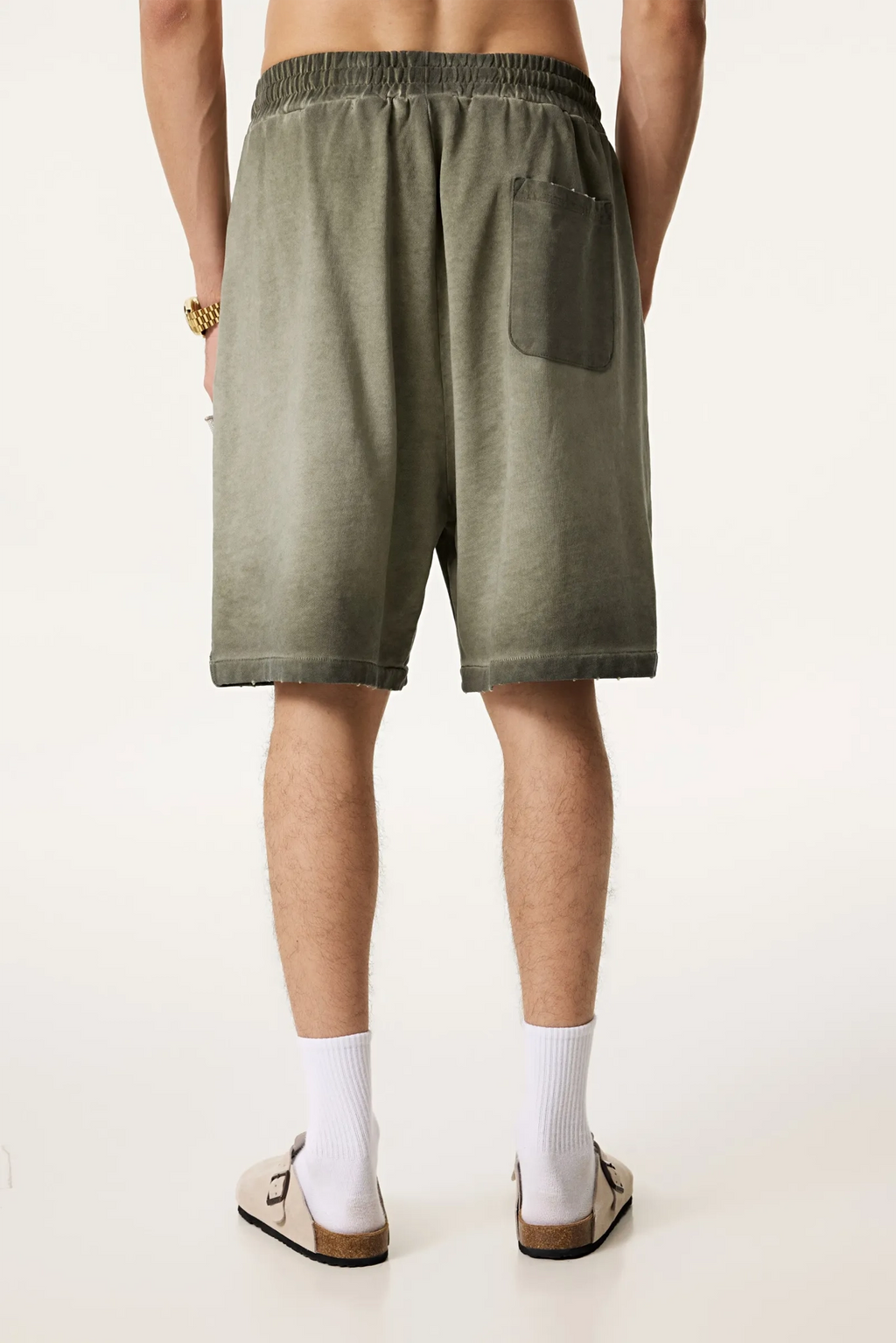 Person wearing olive green shorts on a plain background