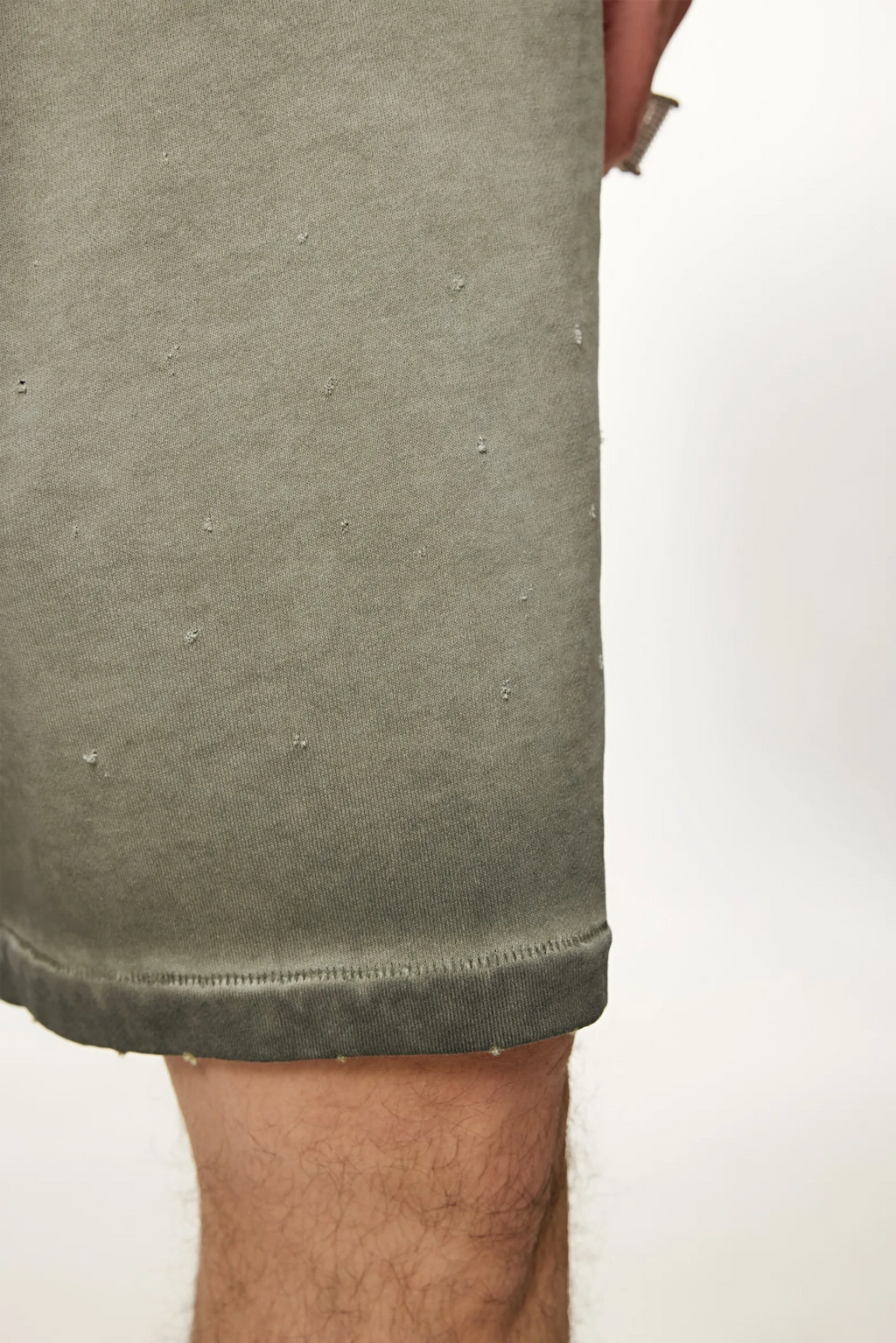 Close-up of a person wearing olive green shorts on a white background