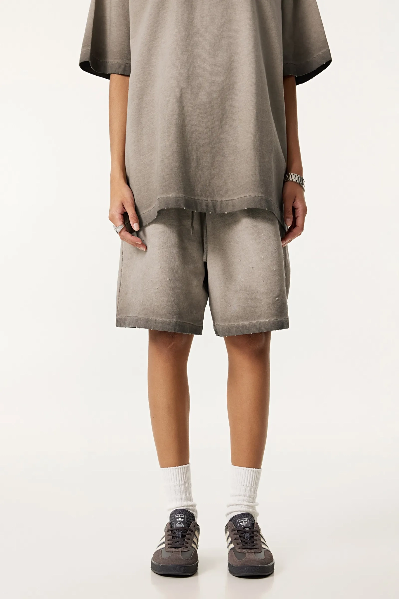 Person wearing a loose-fitting brown t-shirt and shorts set on a white background