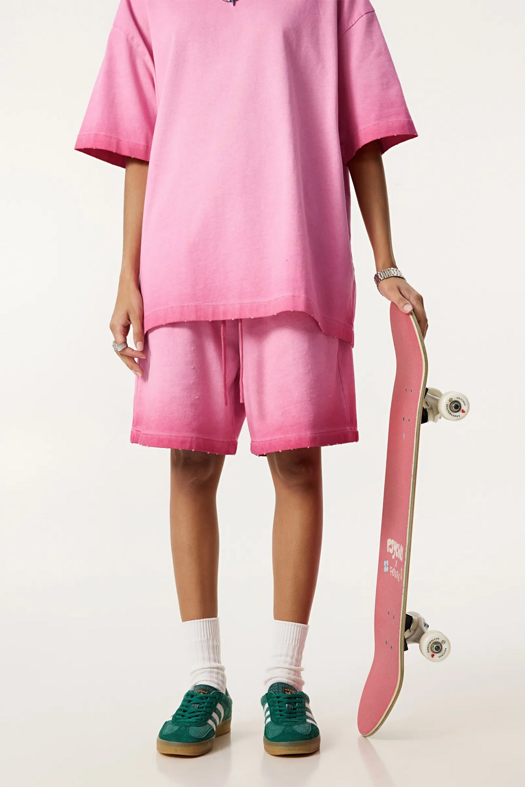 Person wearing a pink outfit with a skateboard on a white background