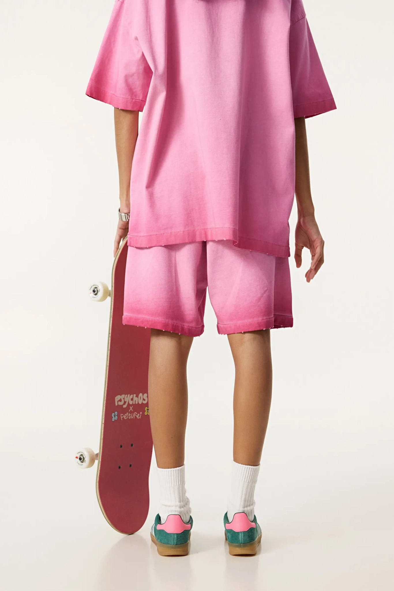Person wearing a pink outfit holding a skateboard on a white background