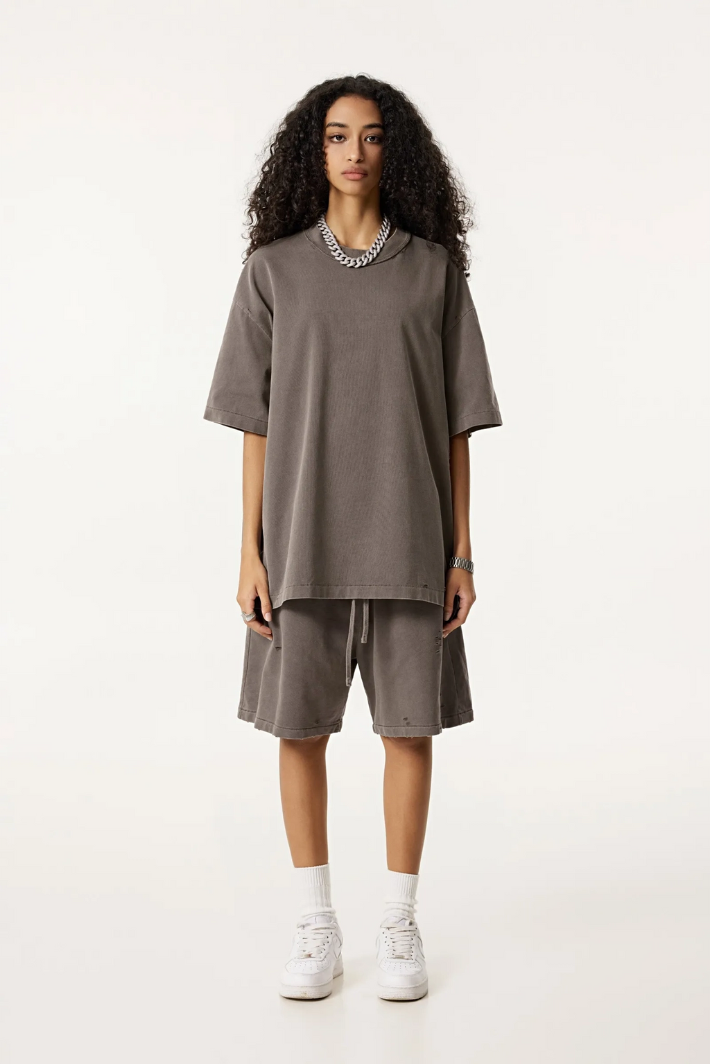 Woman wearing a brown oversized top and shorts set on a white background