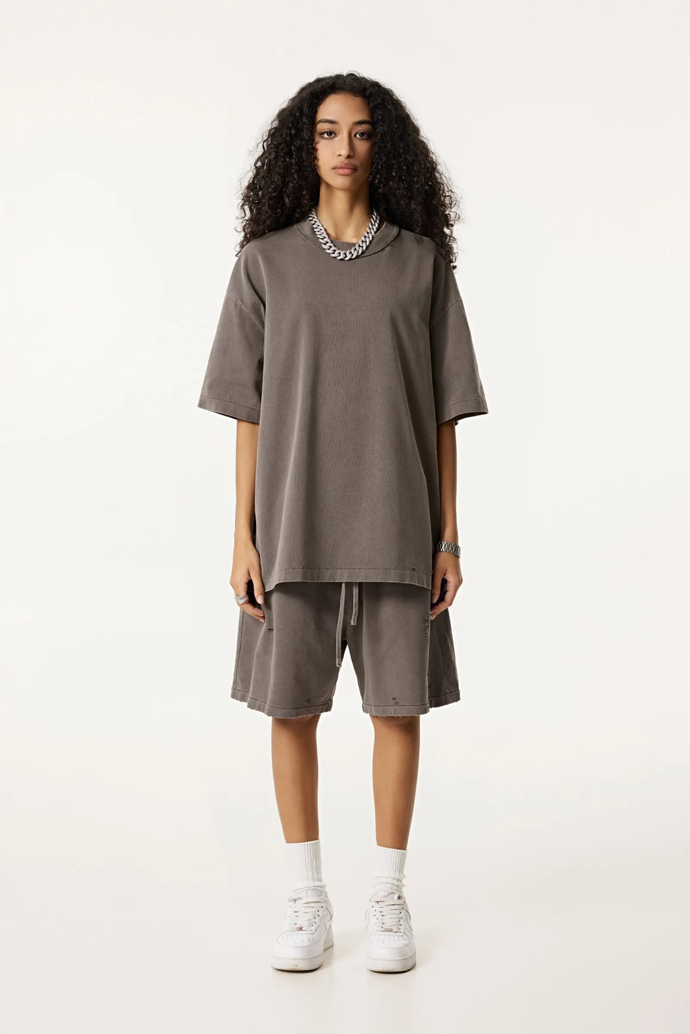 Woman wearing a brown oversized top and shorts set on a white background