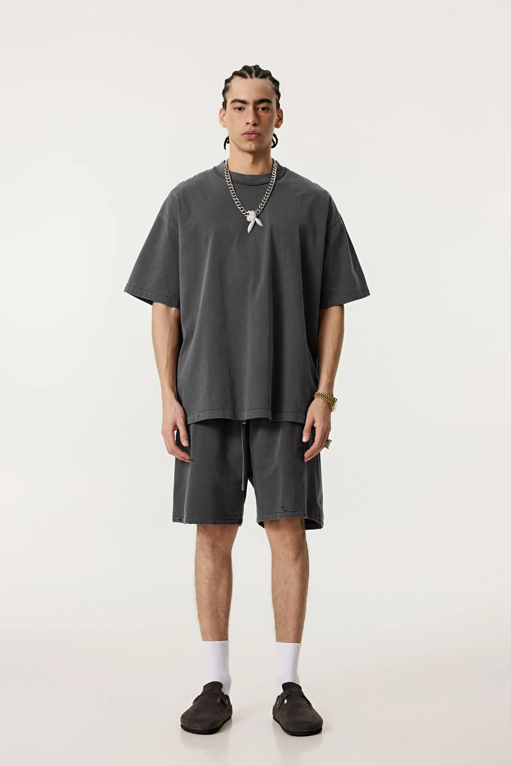 Person wearing a gray oversized t-shirt and shorts set on a white background