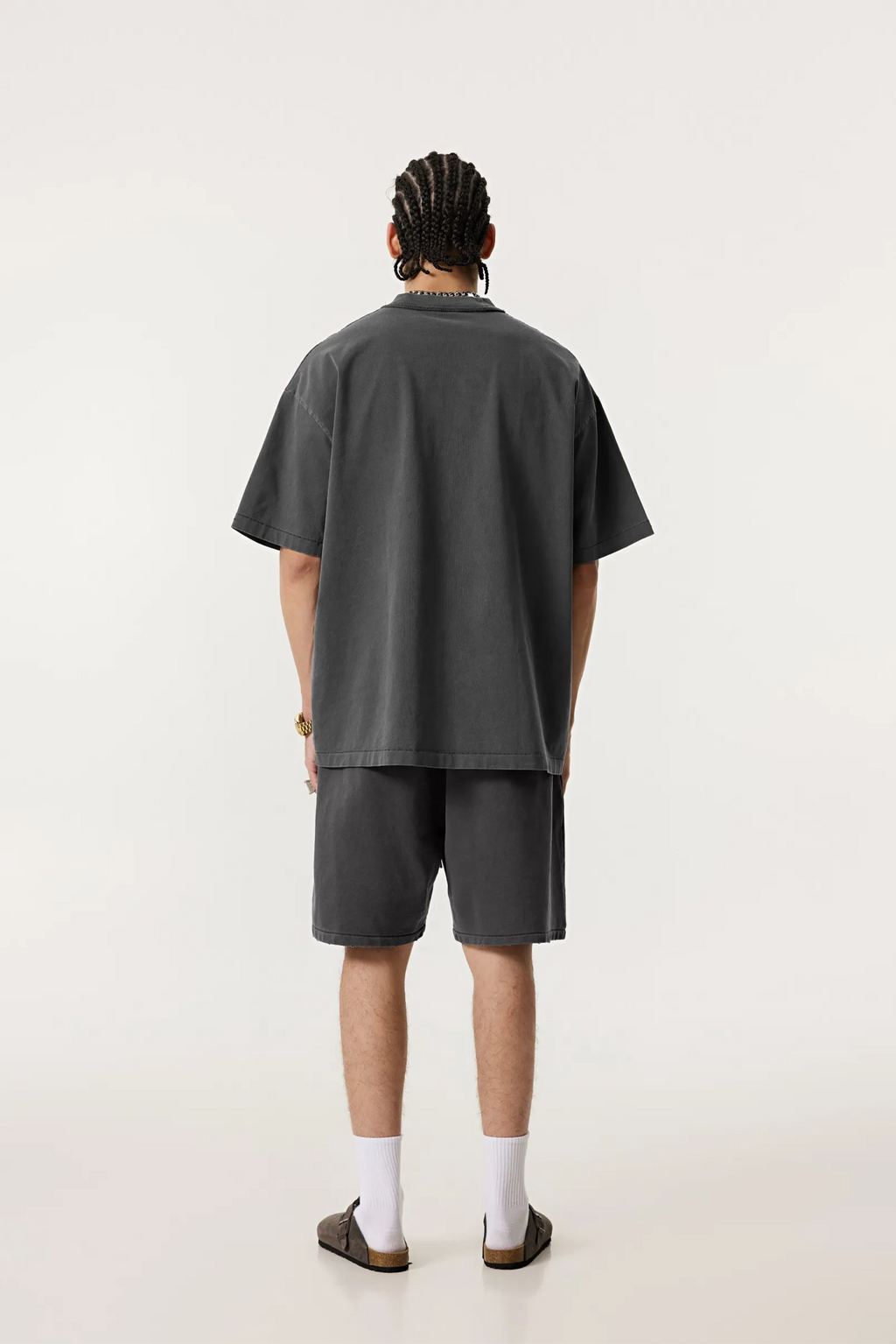 Person wearing a dark gray t-shirt and shorts set on a white background