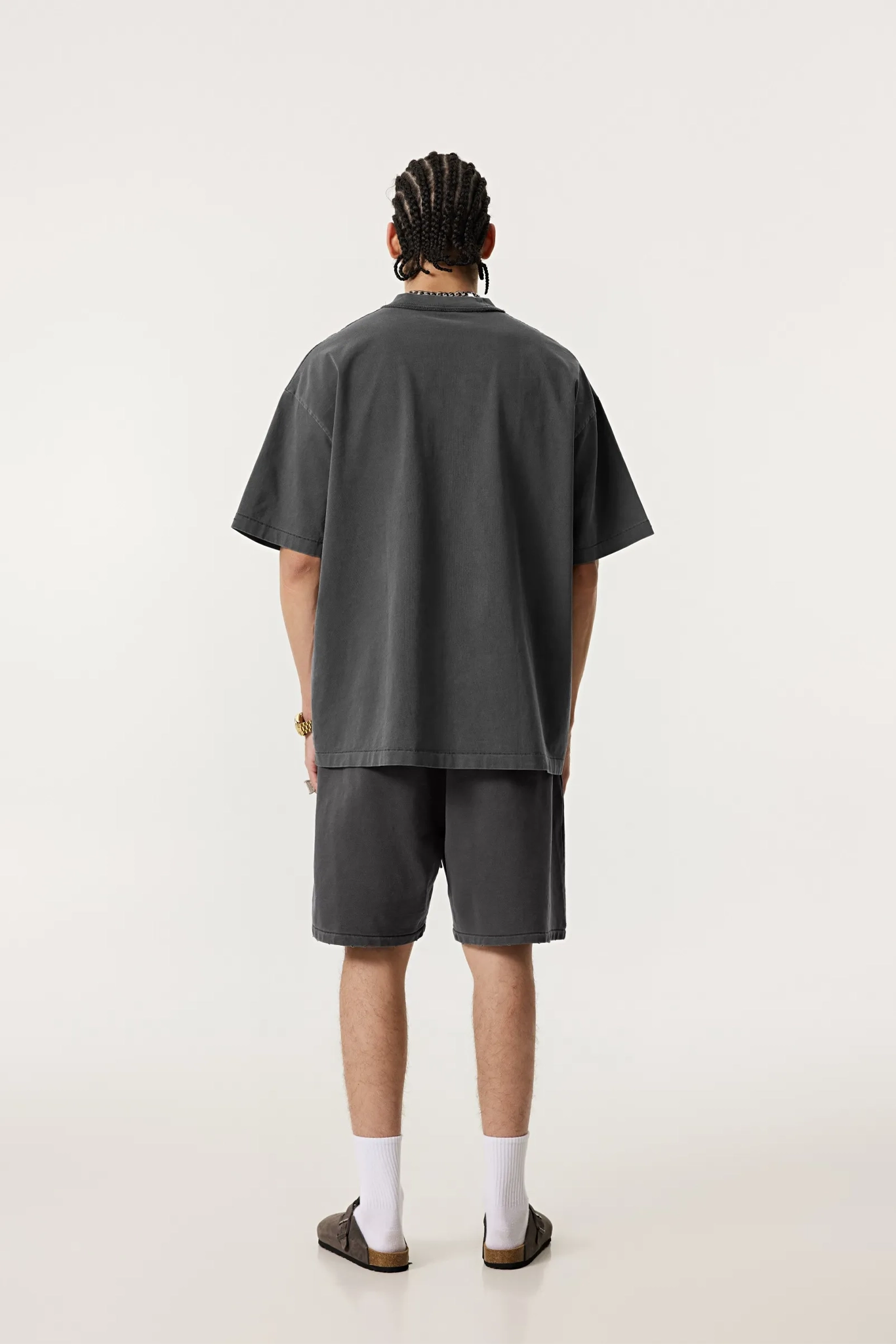 Person wearing a dark gray t-shirt and shorts set on a white background