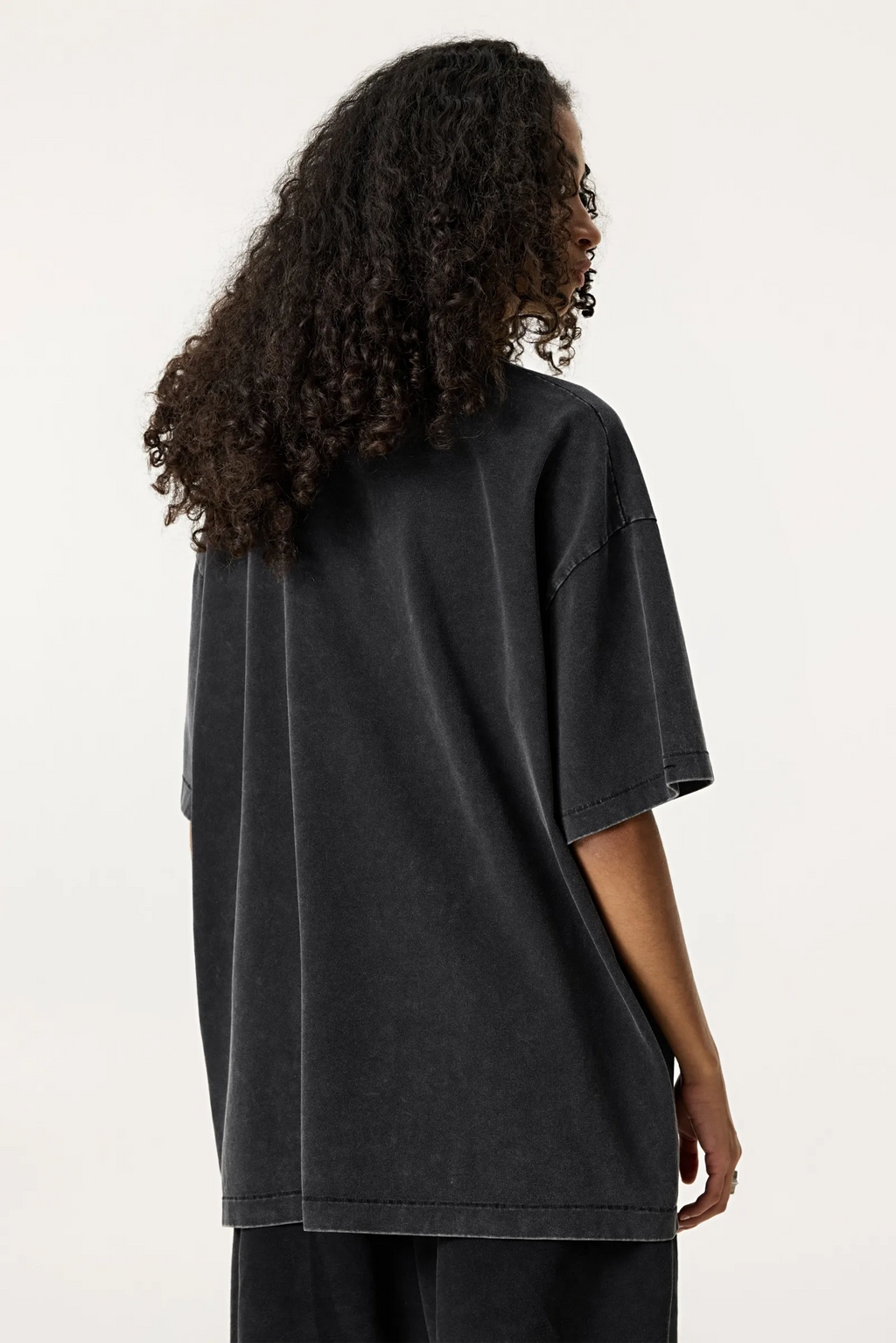 Person wearing a black oversized t-shirt on a white background