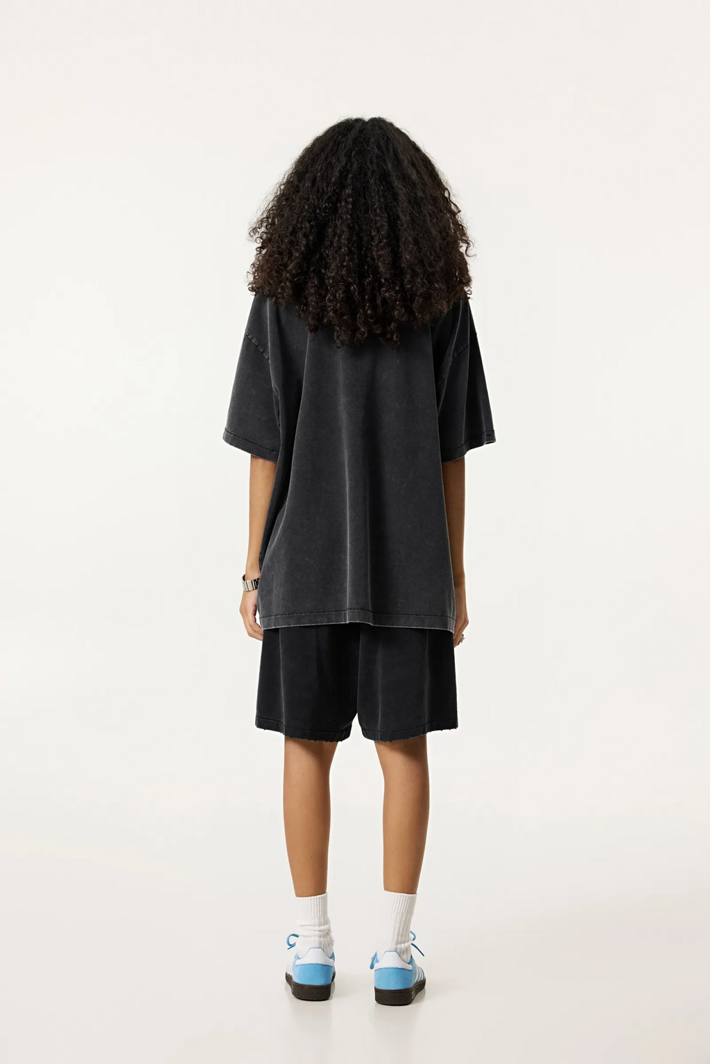 Person wearing a black oversized t-shirt and shorts set on a white background