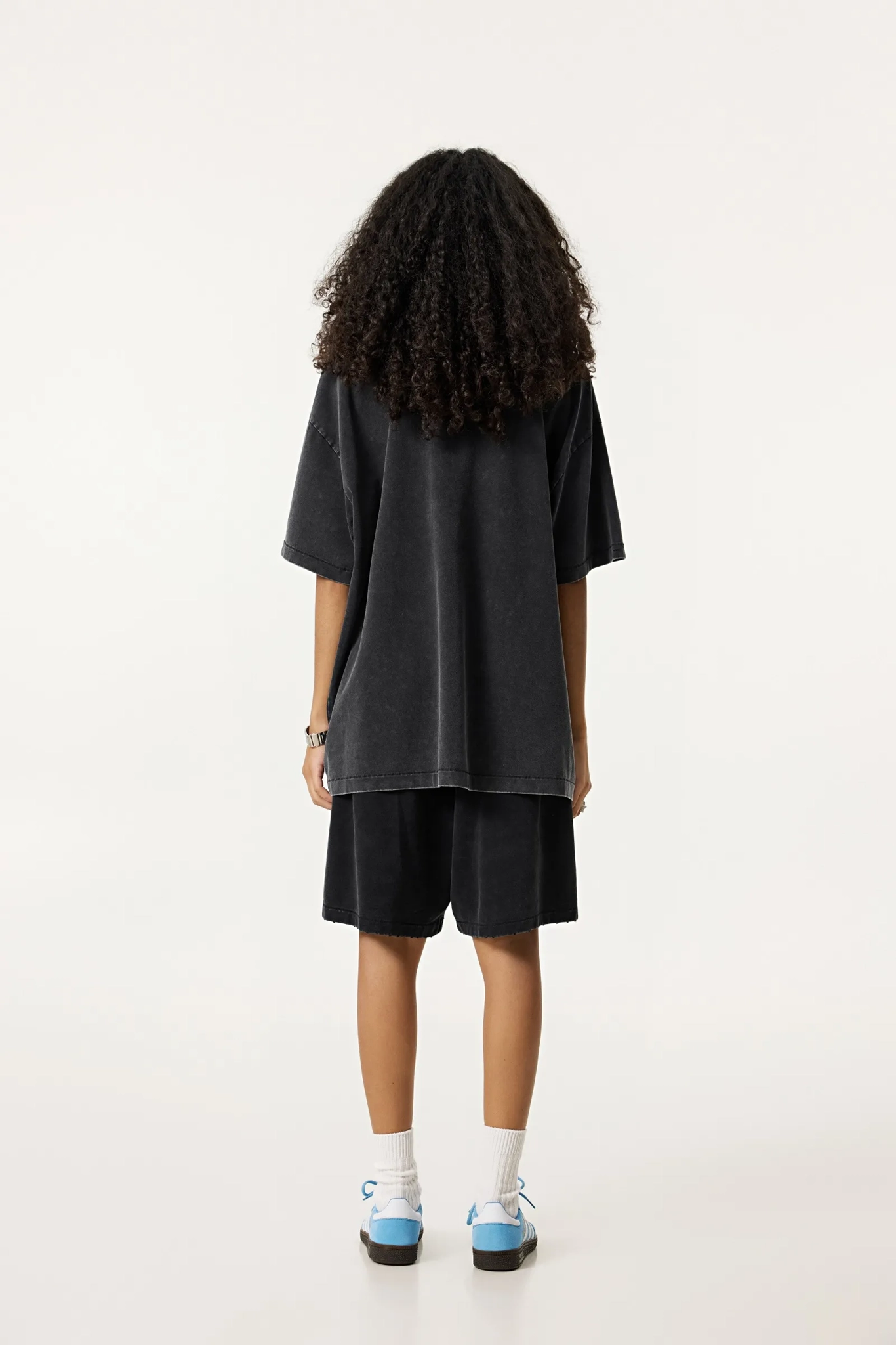 Person wearing a black oversized t-shirt and shorts set on a white background