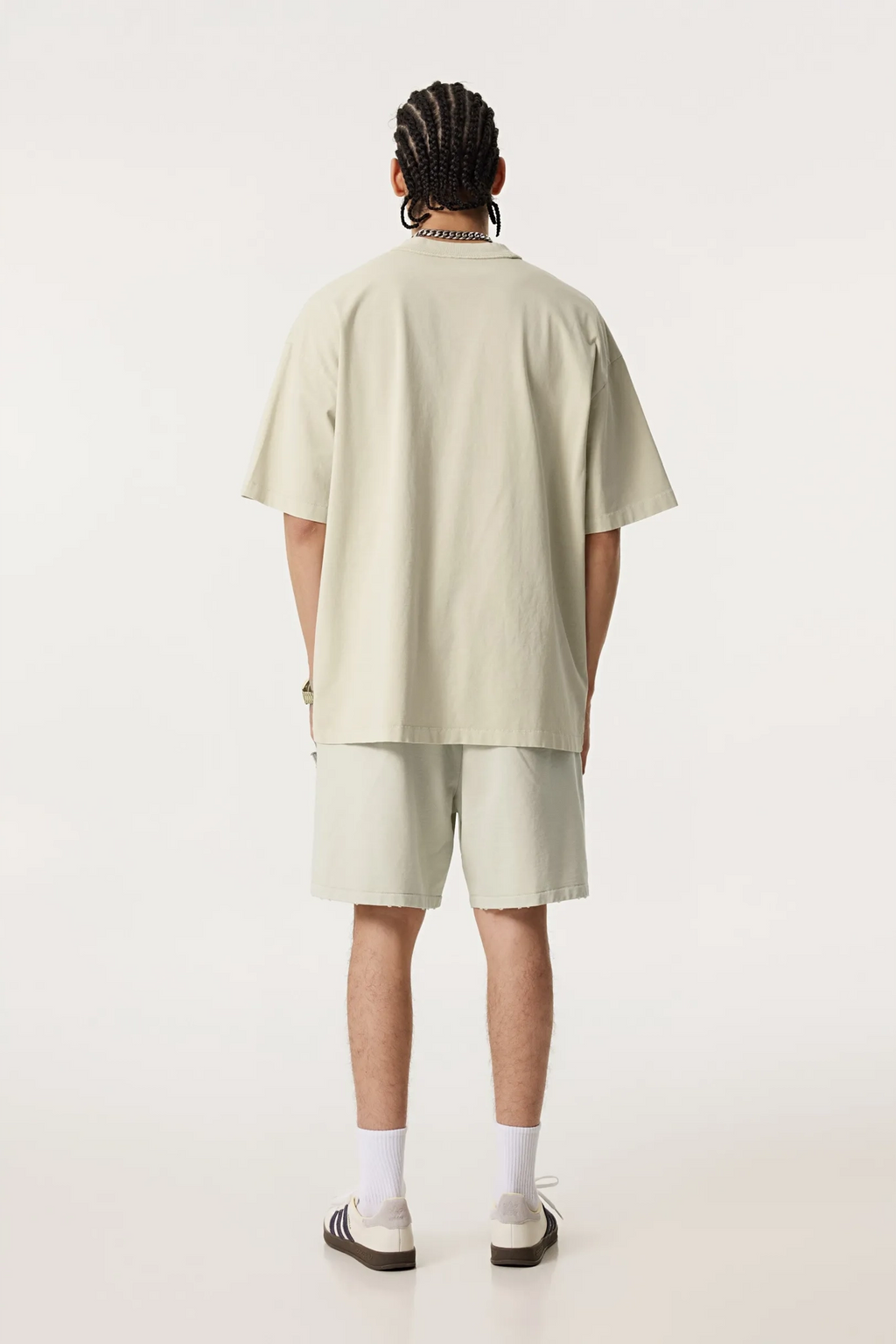 Person wearing a beige t-shirt and shorts set on a white background