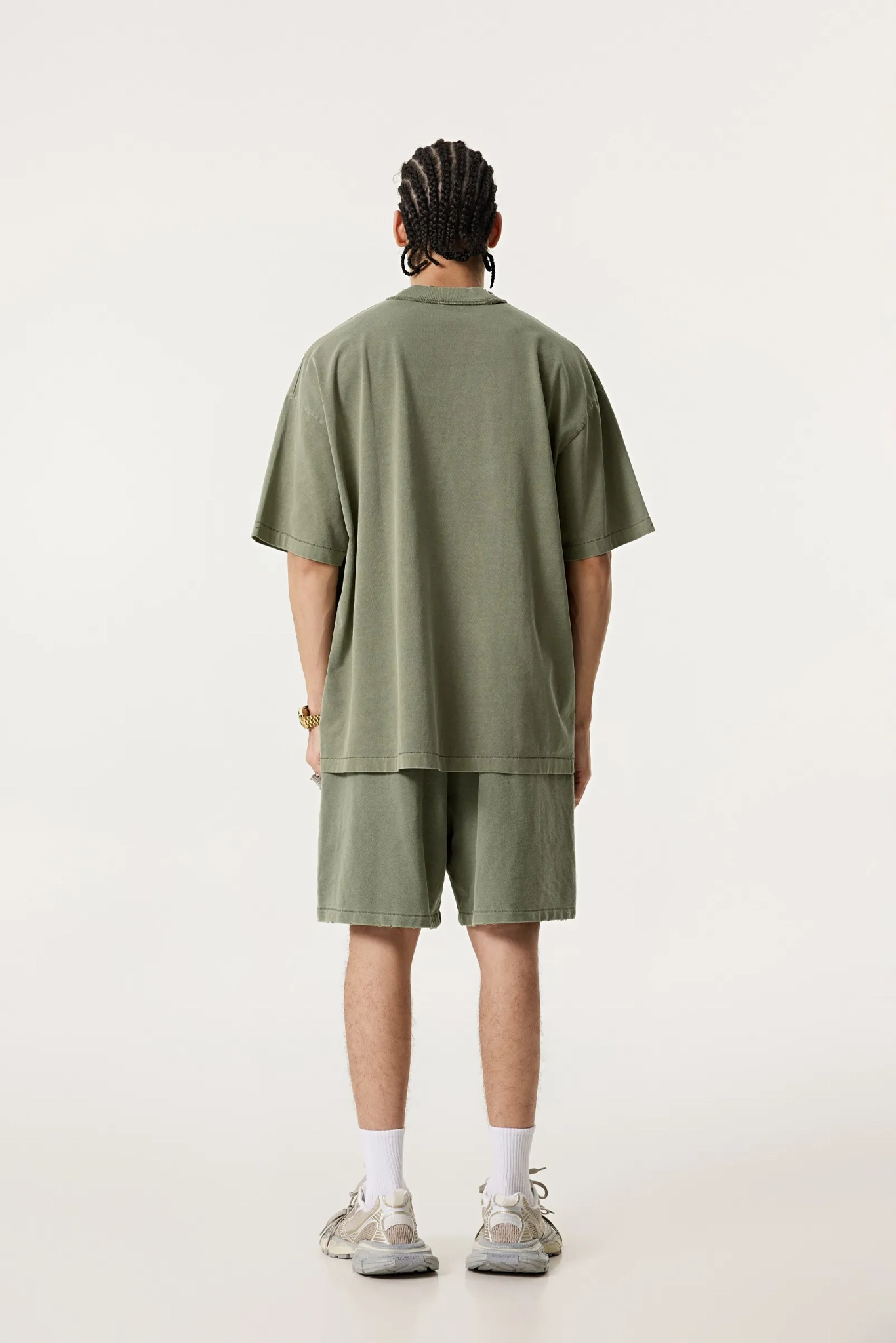 Person wearing a green oversized t-shirt and shorts set on a white background