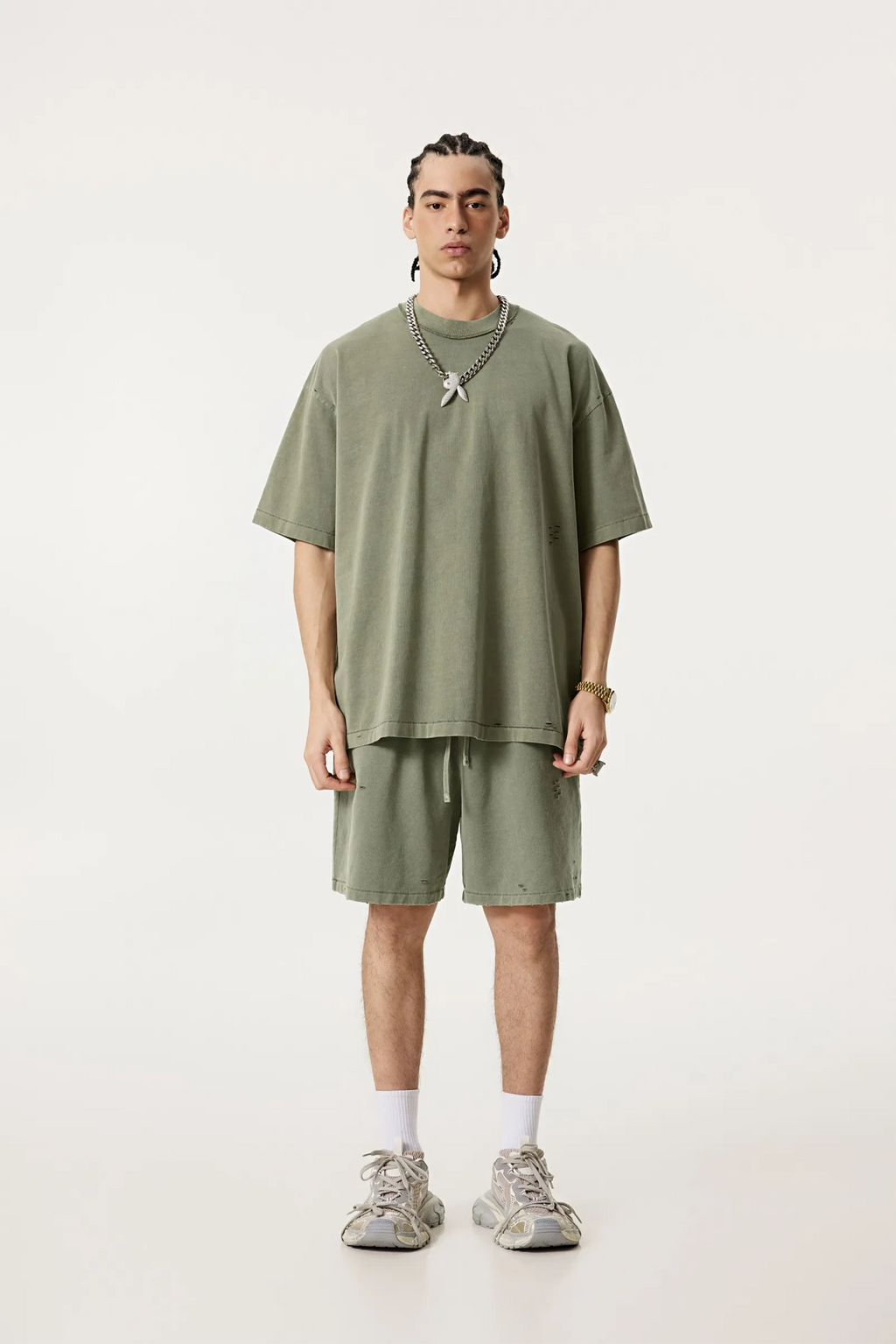 Person wearing a green oversized t-shirt and shorts set on a white background