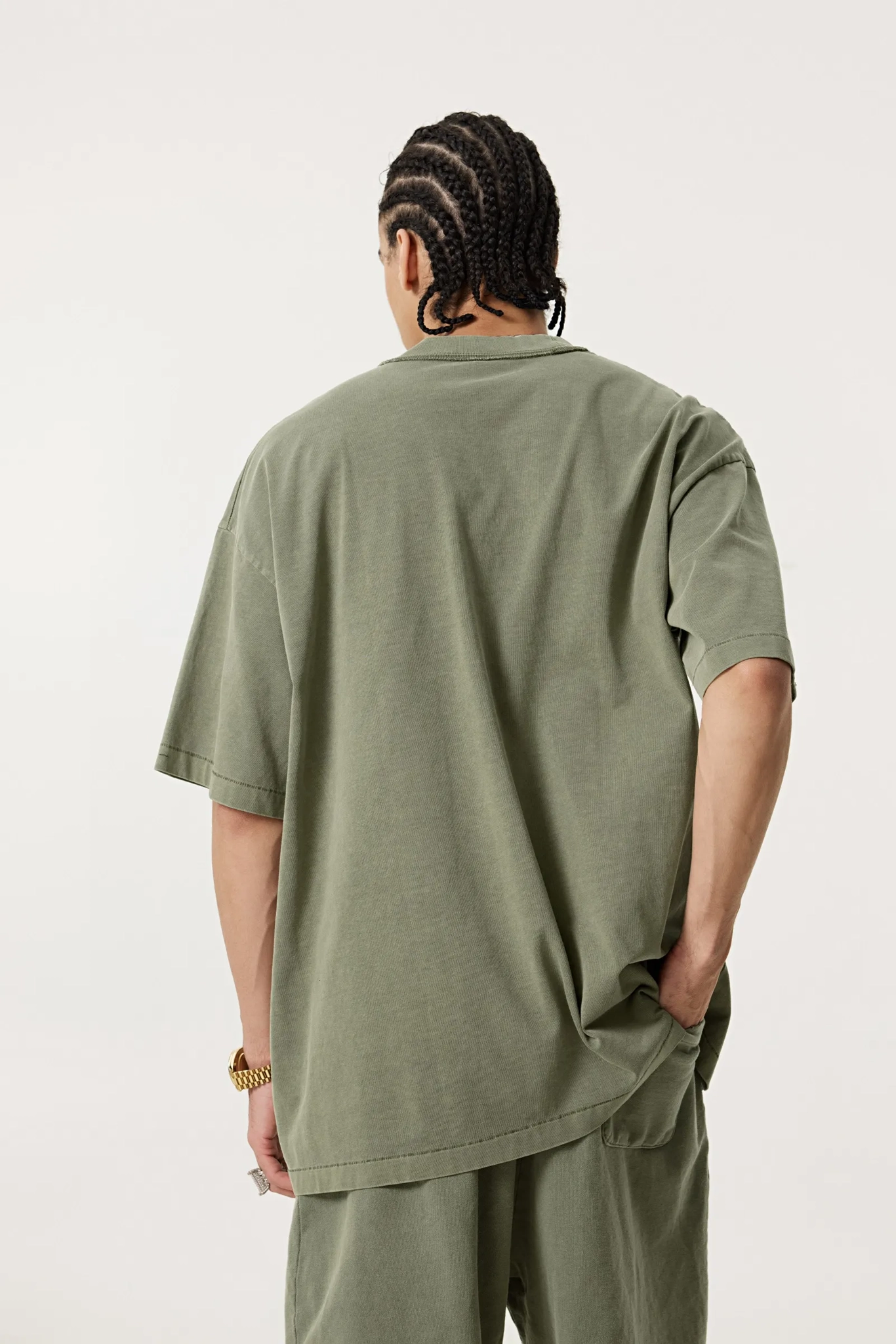 Person wearing an olive green t-shirt and pants on a white background