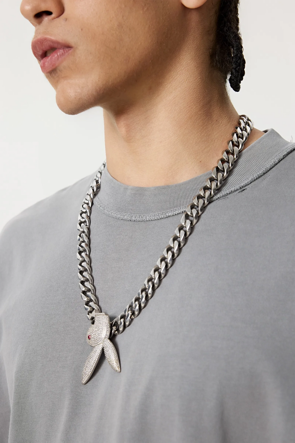 Person wearing a gray shirt with a long chain necklace featuring a butterfly pendant.