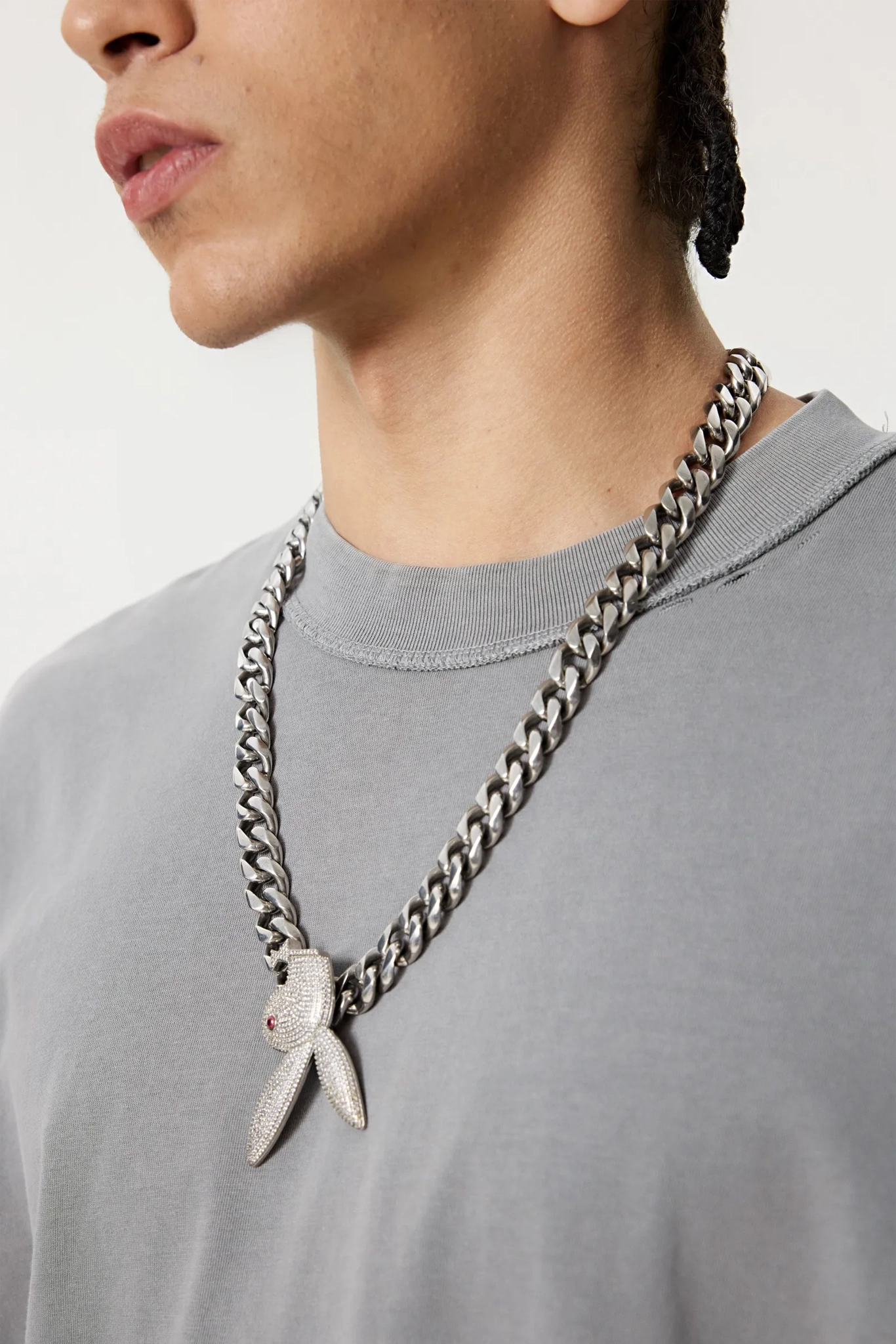 Person wearing a gray shirt with a long chain necklace featuring a butterfly pendant.