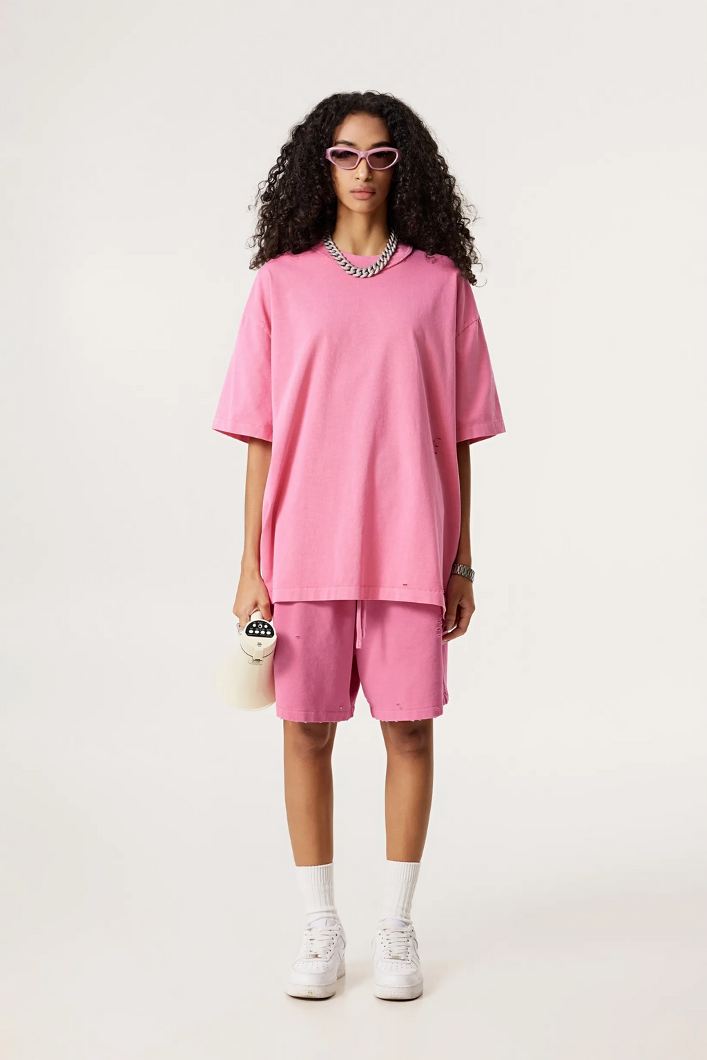 Person wearing a pink outfit with shorts and a top on a white background