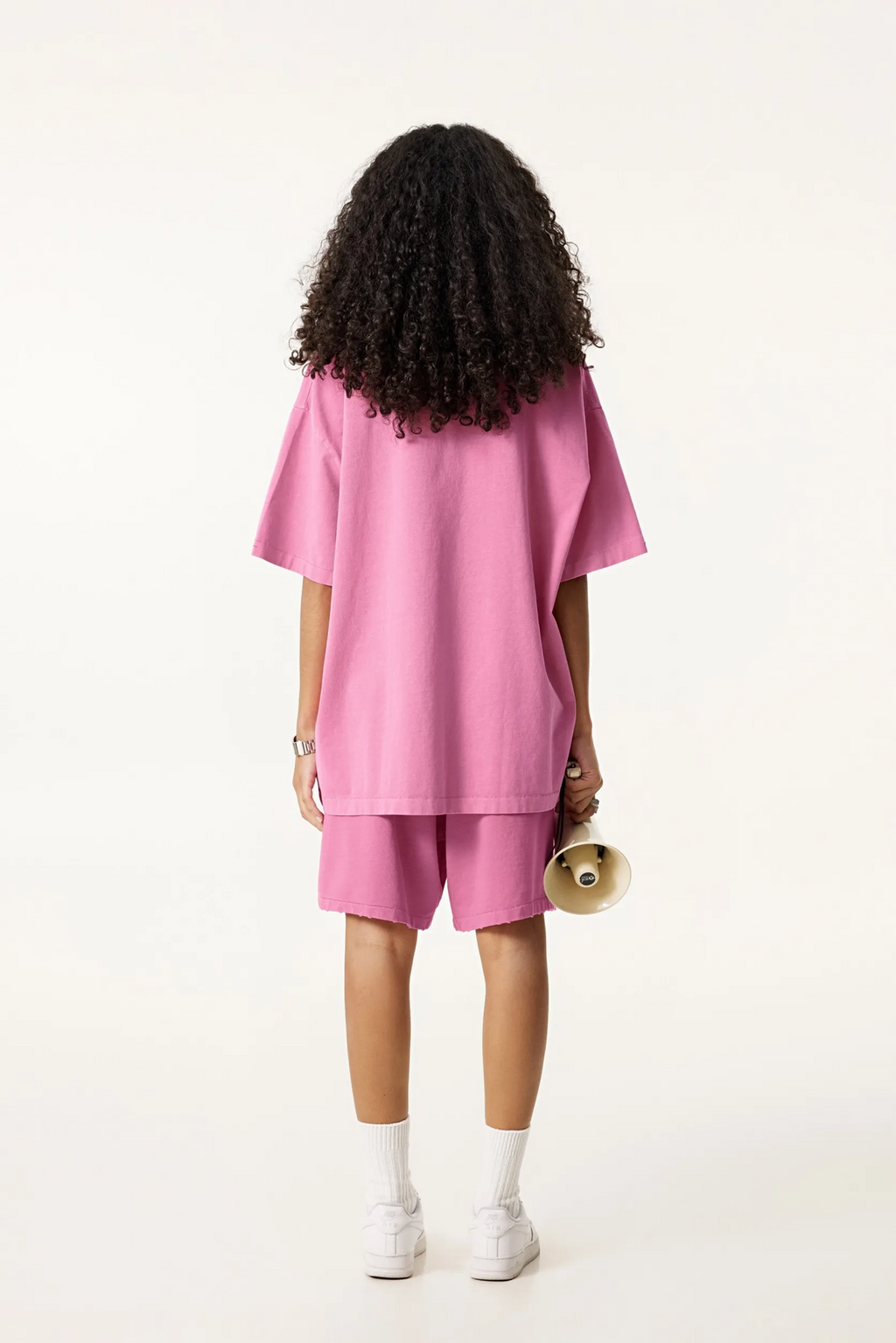Person wearing a pink outfit with shorts on a white background