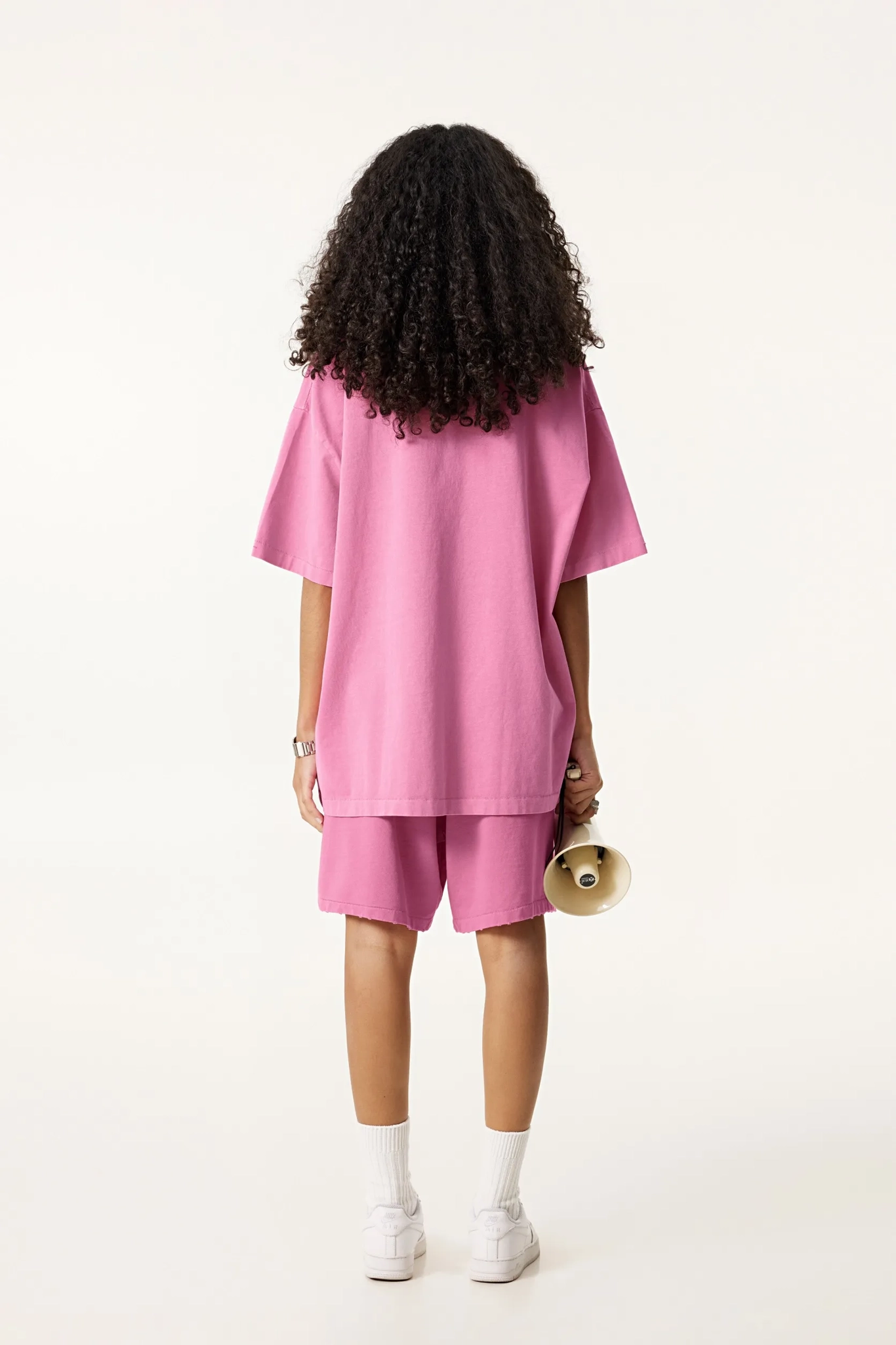 Person wearing a pink outfit with shorts on a white background