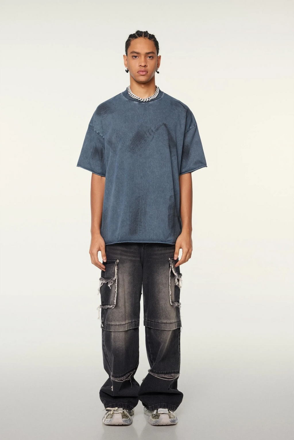 Person wearing a blue oversized t-shirt and black distressed jeans on a white background