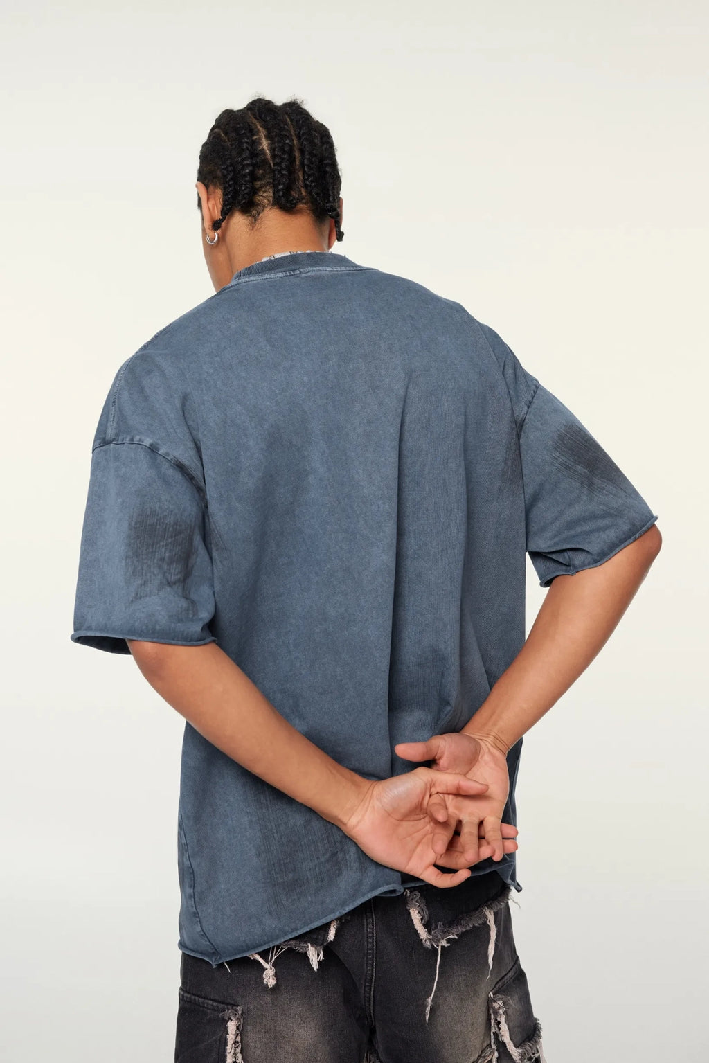 Person wearing a blue denim shirt and ripped jeans against a white background