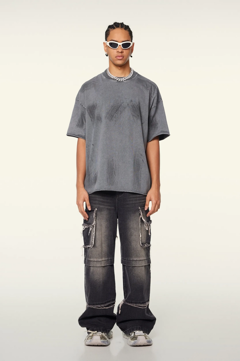 Person wearing a gray oversized t-shirt and black cargo pants on a white background