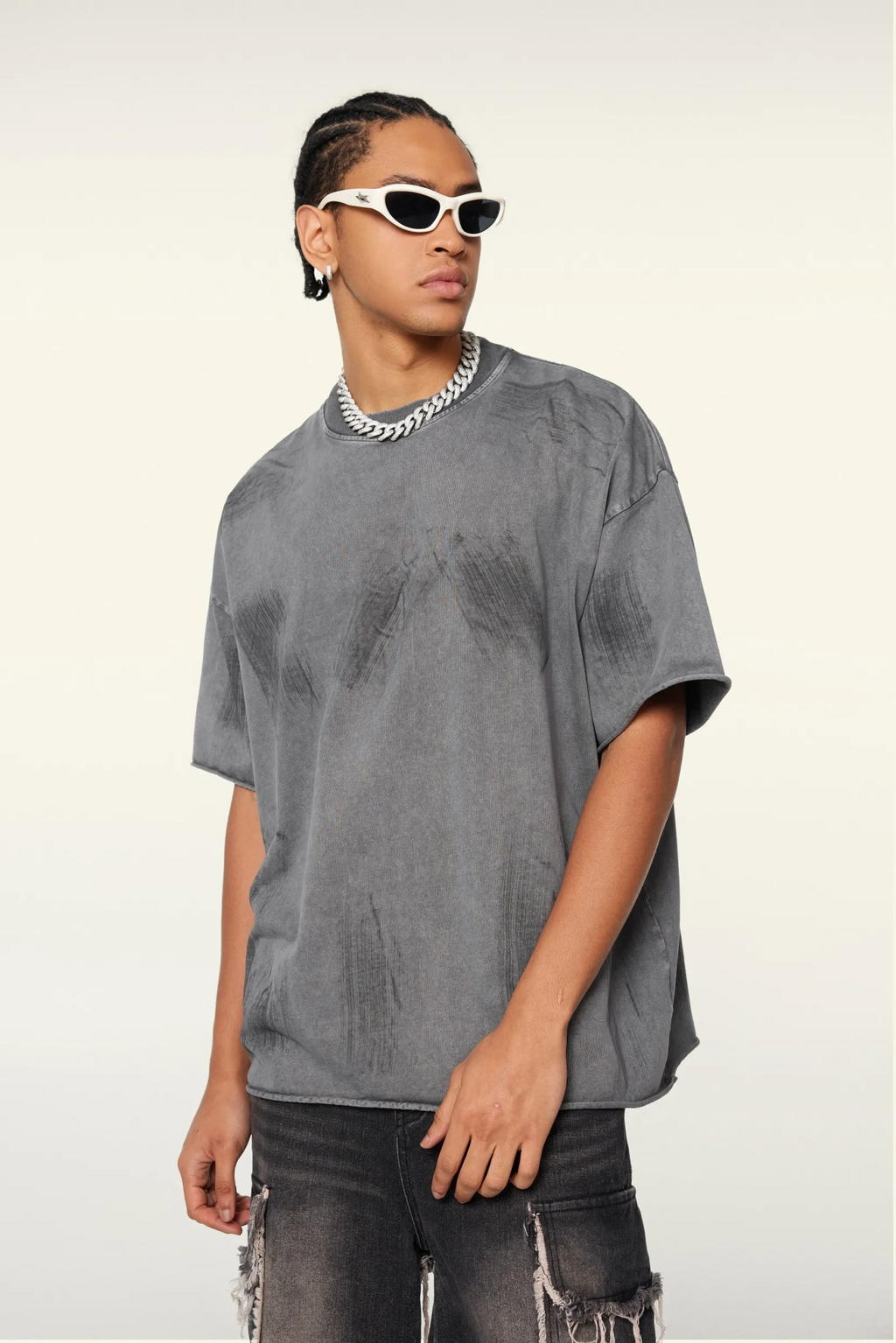Person wearing a gray oversized t-shirt and sunglasses on a white background