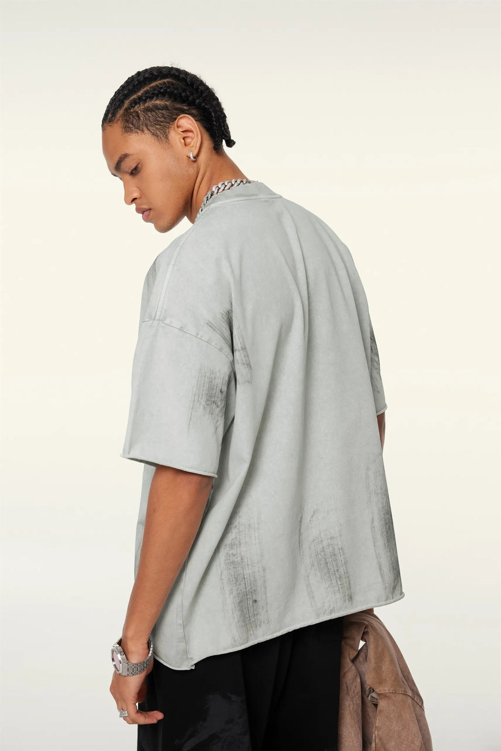 Person wearing a light gray oversized shirt with a white background