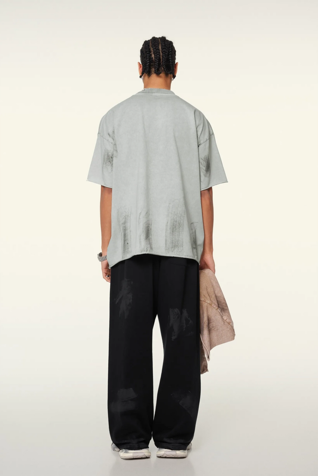 Person wearing a light gray t-shirt and black pants on a white background