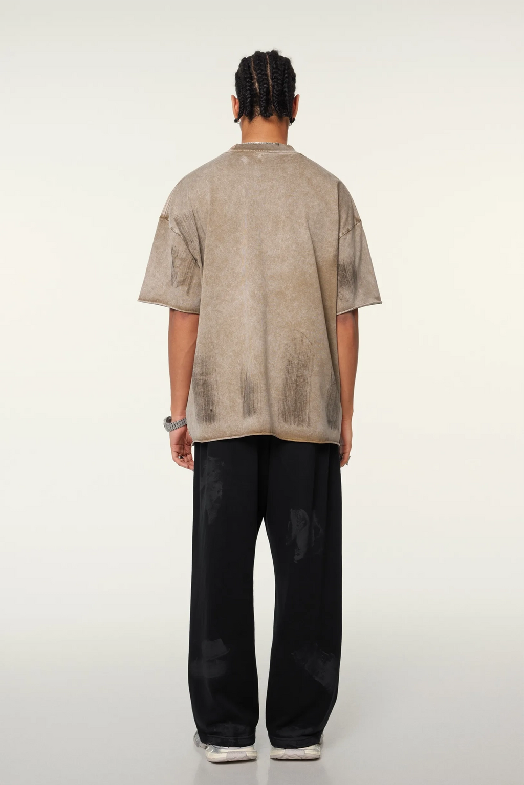 Person wearing a beige shirt and black pants on a white background