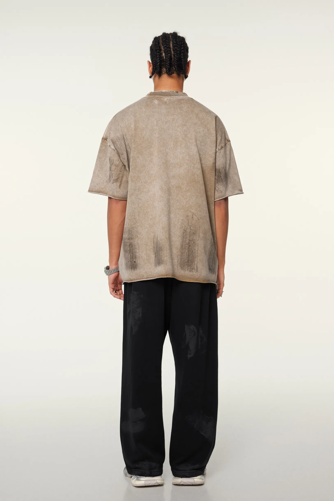 Person wearing a beige shirt and black pants on a white background